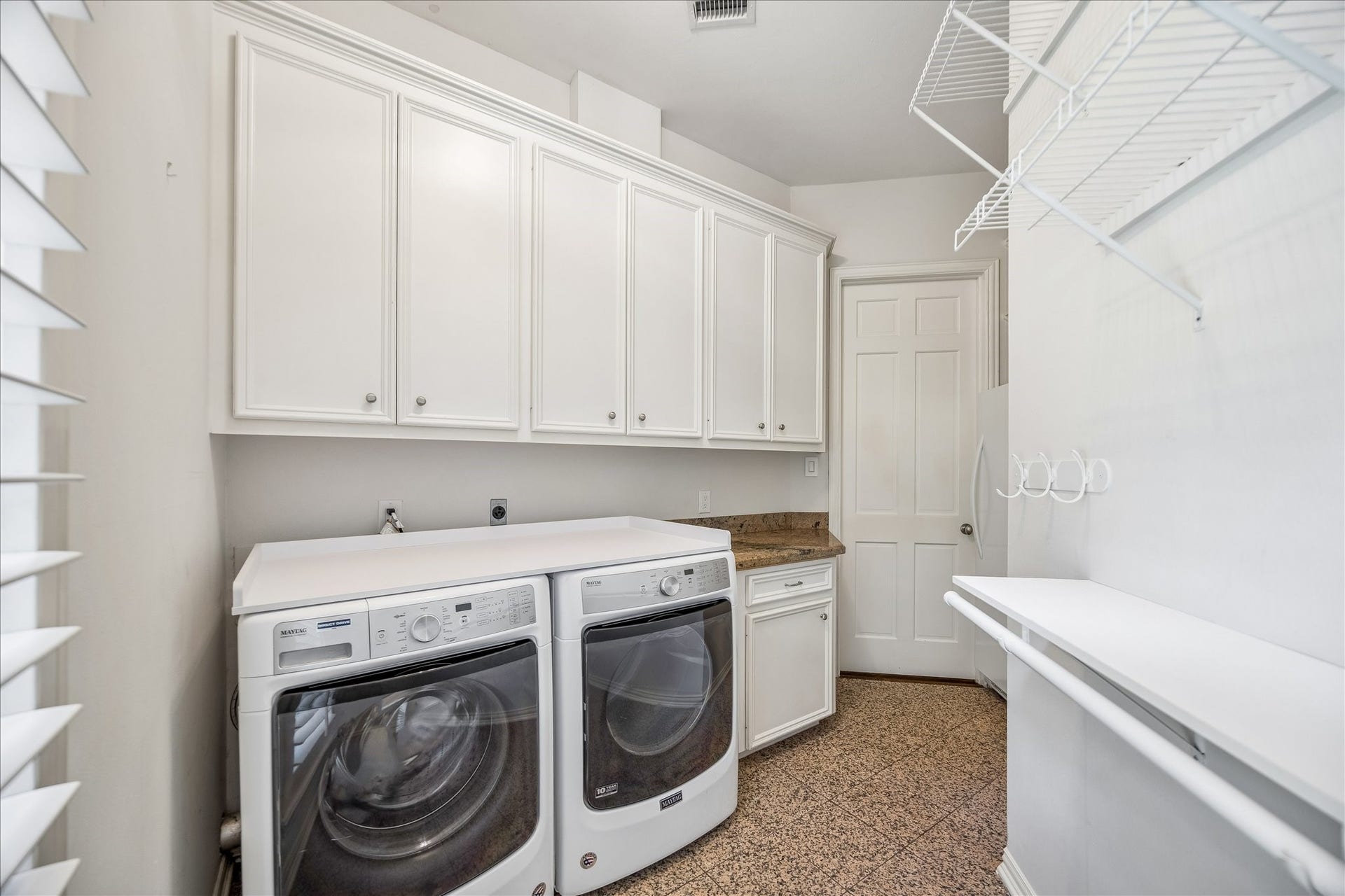 This bright, highly functional laundry room features a washer and dryer set, included with the price of the home, along with an second refrigerator for added convenience. Crisp white cabinetry provides ample storage for great organization. Finished in clean, neutral tones, this space offers a polished and well-organized utility area.