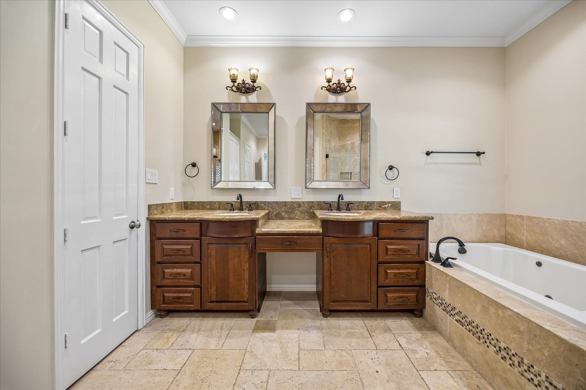 This spa-like primary bath offers a double vanity with elegant wood cabinetry, granite countertops, and stylish framed mirrors. The primary bath is complemented by thoughtfully designed his-and-her closets, providing ample personal storage space