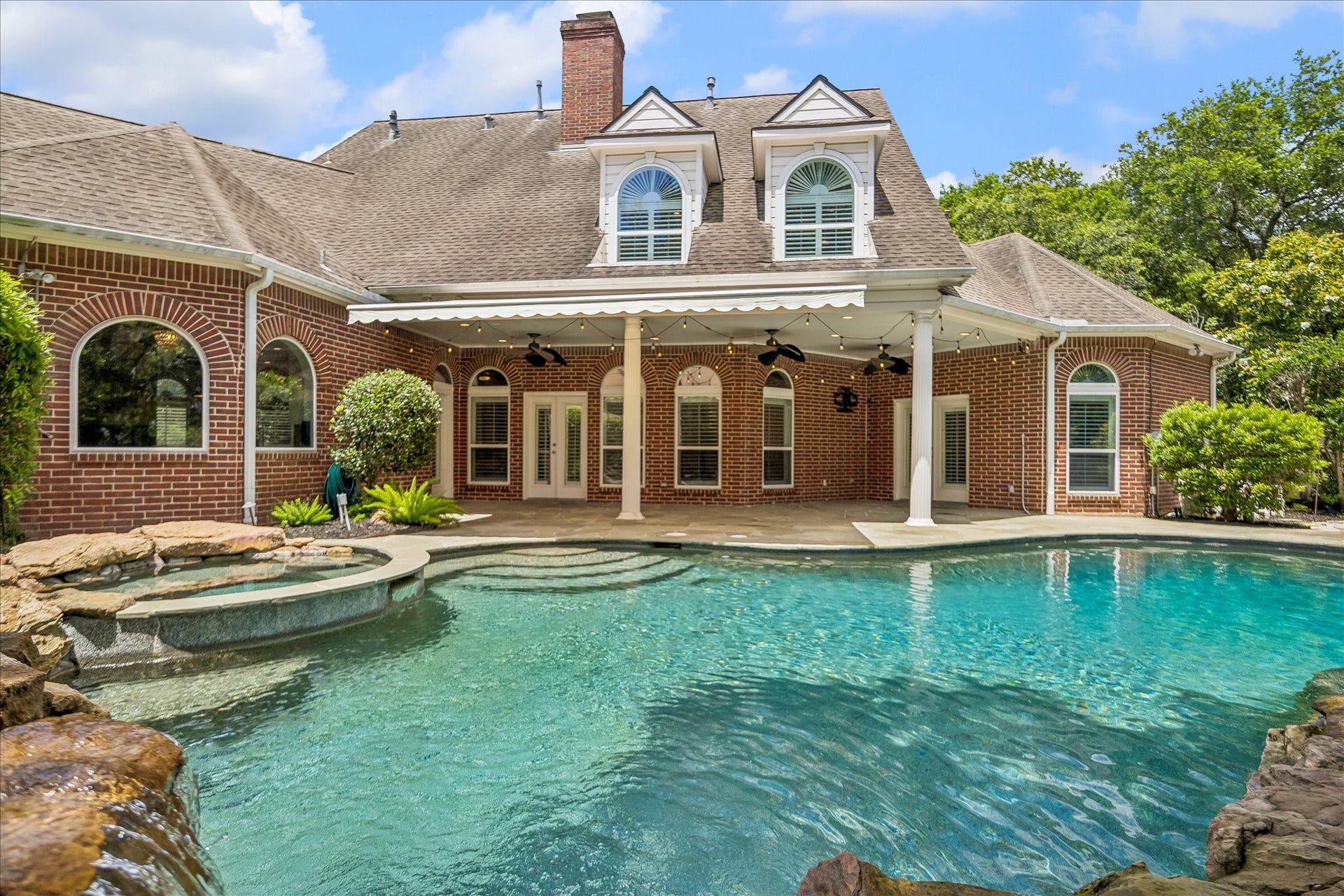 This stunning brick home features a spacious backyard with a beautiful swimming pool and spa, complemented by a covered patio with ceiling fans. Perfect for outdoor entertaining and relaxation.