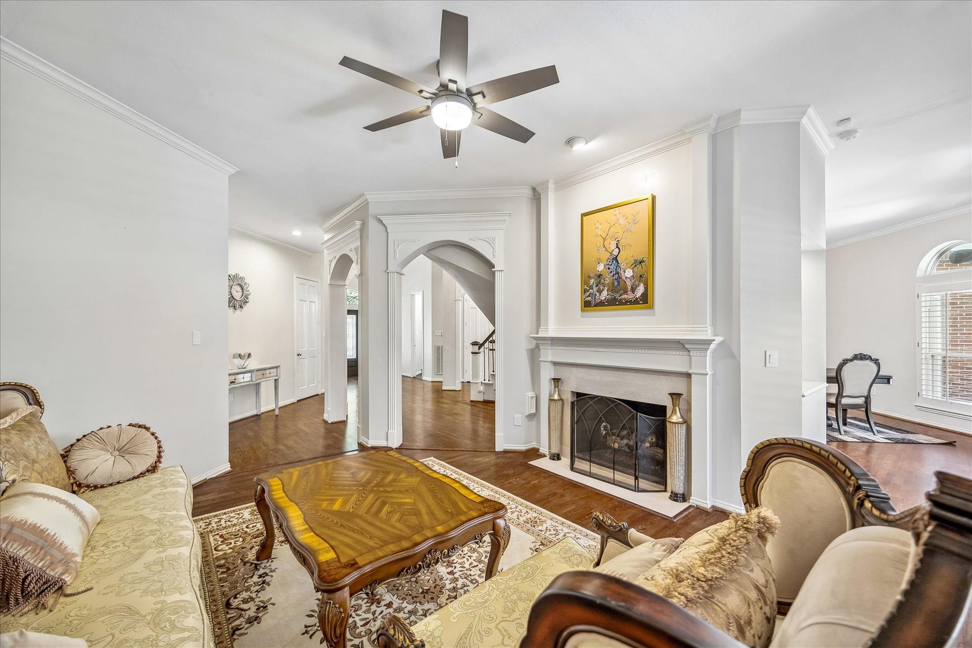 Lovely living room featuring a cozy fireplace, elegant crown molding, and graceful archways.
