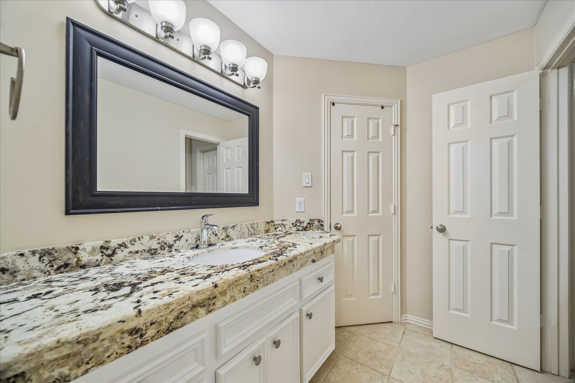 The adjoining portion of the Jack and Jill bathroom continues the cohesive, thoughtfully updated design, featuring neutral-toned walls and tile flooring. The space maintains a clean, modern aesthetic with a refined simplicity.