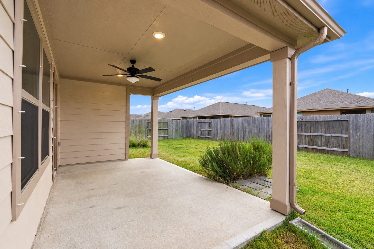 10314 Russell Pines Drive, Rosharon, TX 77583 Charming covered patio with a ceiling fan overlooks a spacious fenced backyard, perfect for outdoor relaxation and family fun.