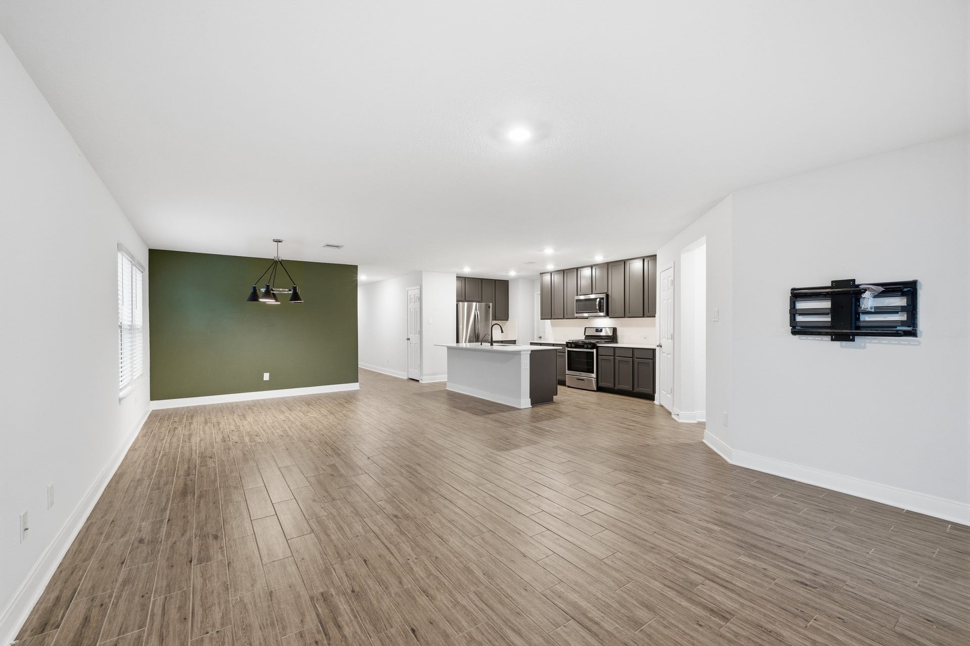 10314 Russell Pines Drive, Rosharon, TX 77583 Spacious open-concept living area featuring sleek flooring, a modern kitchen with stainless steel appliances, and a stylish accent wall perfect for dining.
