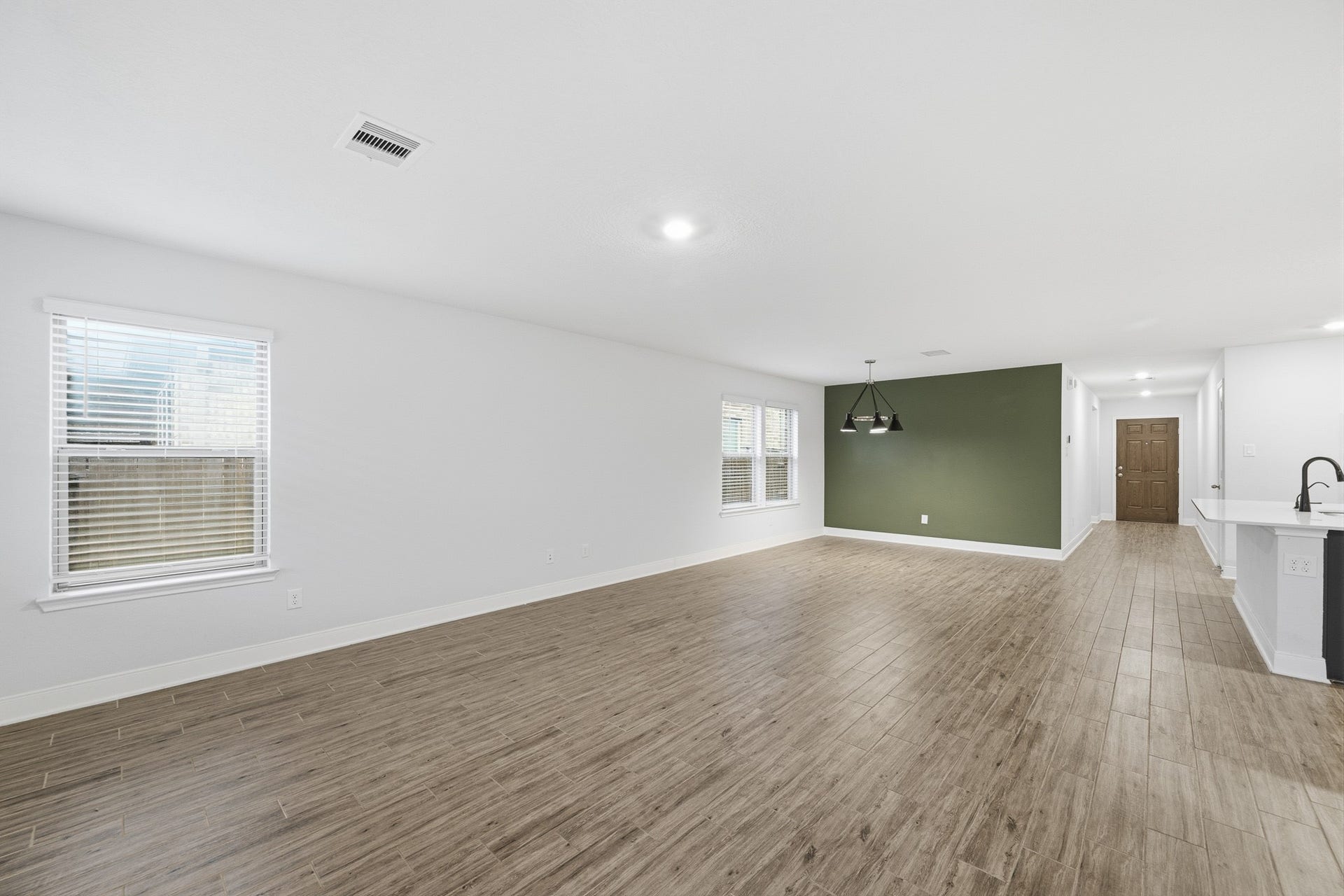 10314 Russell Pines Drive, Rosharon, TX 77583 Spacious open-concept living and breakfast area with sleek flooring and a stylish accent wall, perfect for modern living and entertaining.