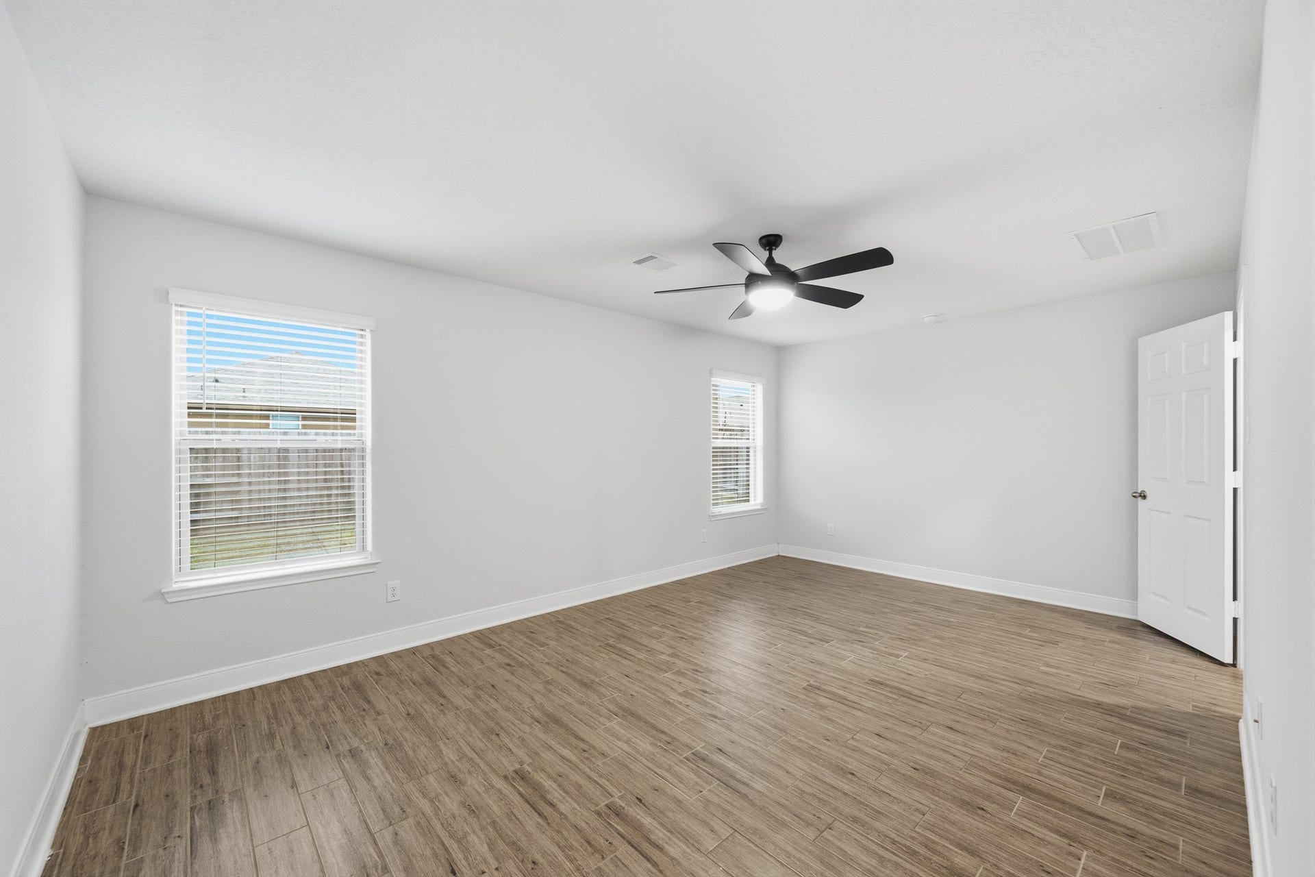 10314 Russell Pines Drive, Rosharon, TX 77583 Bright and spacious room featuring sleek flooring, a modern ceiling fan, and ample natural light from two large windows.