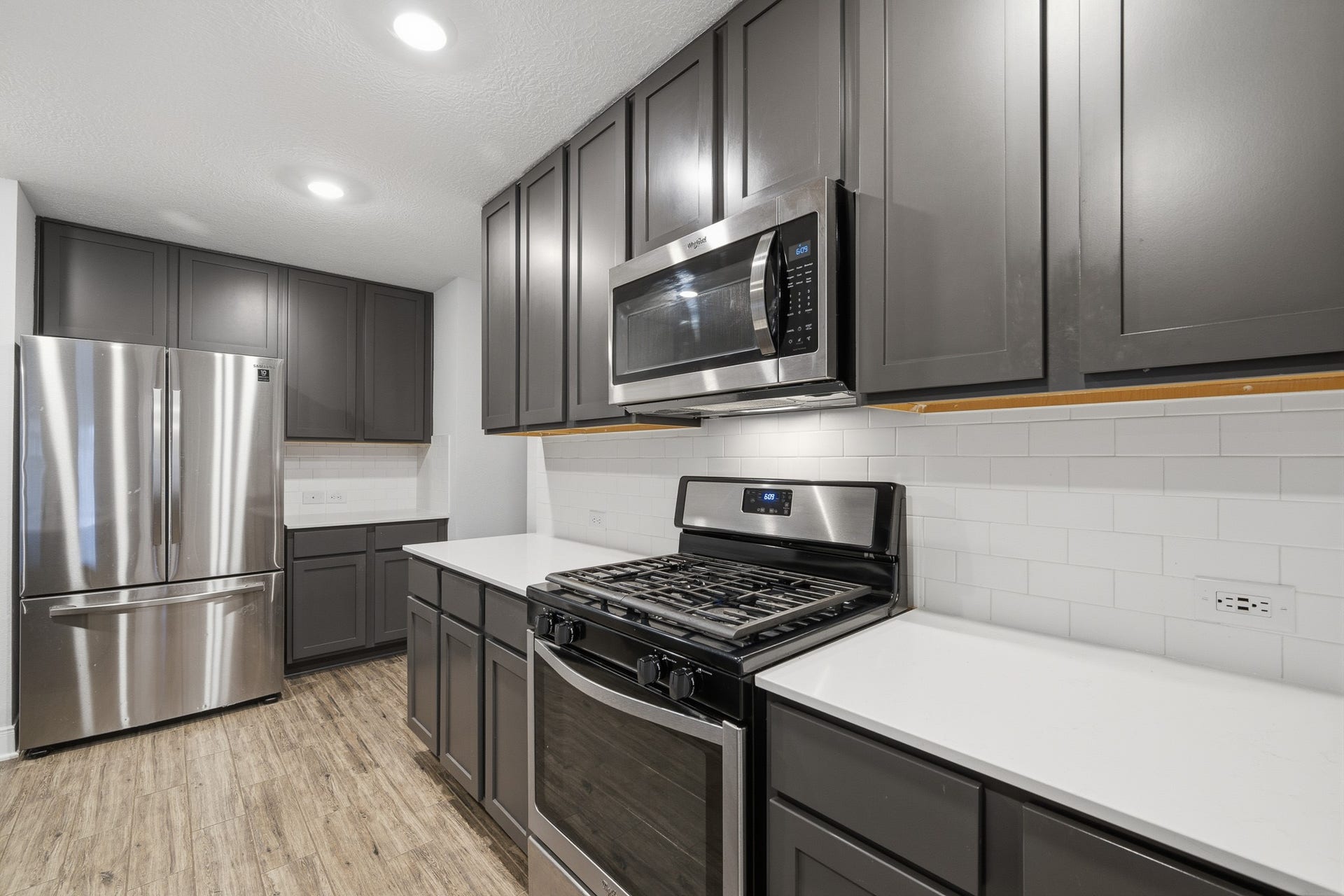 10314 Russell Pines Drive, Rosharon, TX 77583 Sleek and modern kitchen featuring stainless steel appliances, elegant dark cabinetry, and a bright subway tile backsplash.