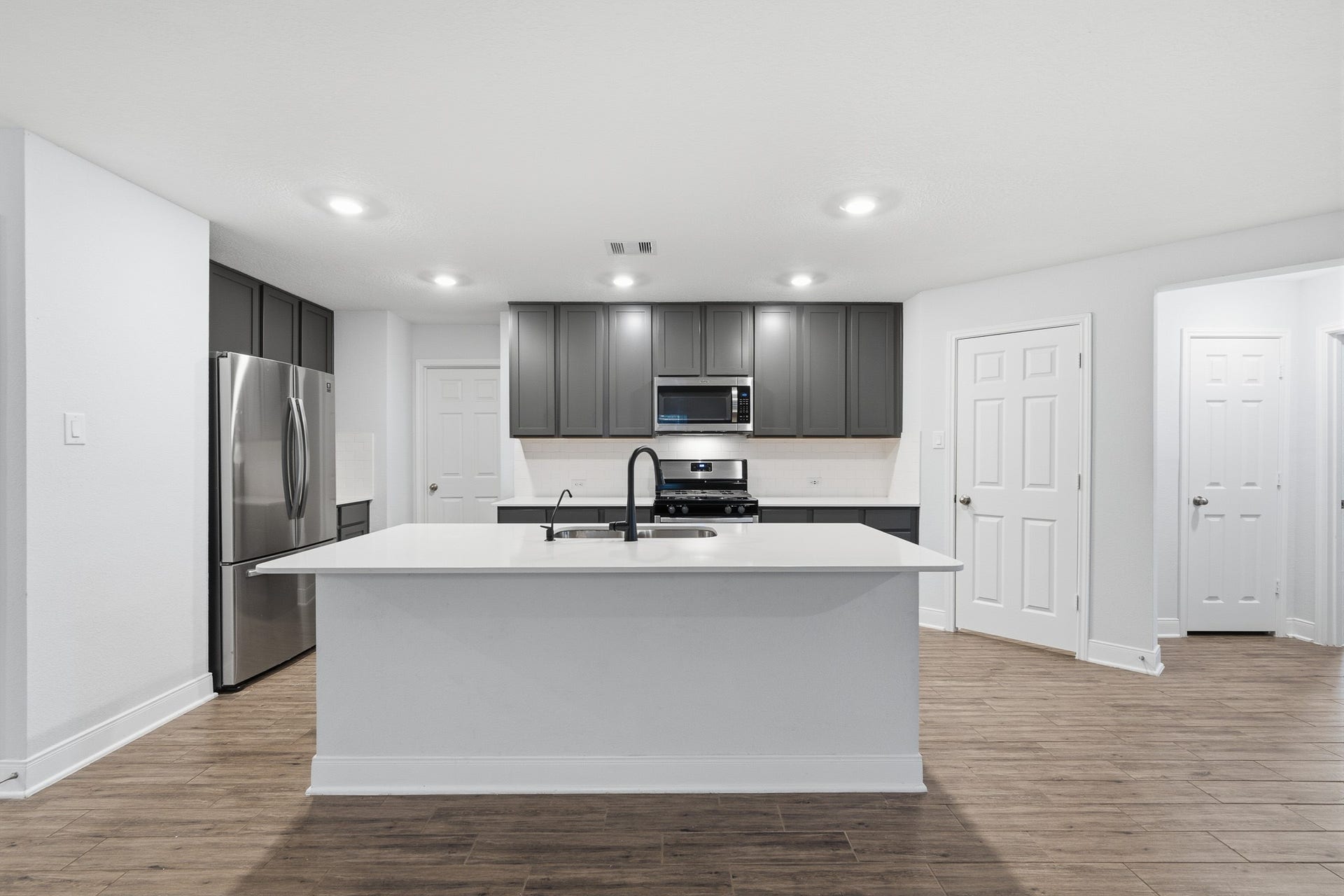 10314 Russell Pines Drive, Rosharon, TX 77583 Modern kitchen featuring sleek dark cabinetry, stainless steel appliances, and a spacious island with a stylish sink.