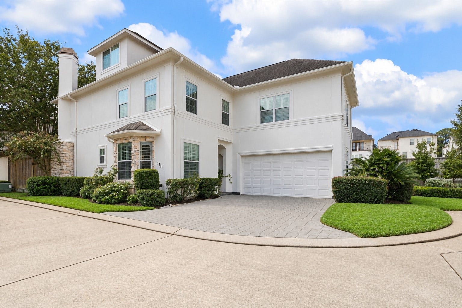 1311 N Jordan Cove, Houston, TX 77055 Another view of this lovely home highlighting the covered entry w/ recessed lighting, attached 2-car garage w/ built-in storage & EV charging outlet, and double-wide driveway. Wonderful lock & leave lifestyle w/ HOA dues covering water, twice-weekly trash collection, weekly basic lawn maintenance & common area maintenance. Conveniently located near major freeways, Downtown, Galleria & Energy Corridor! (Photo virtually enhanced to show power-washed driveway).