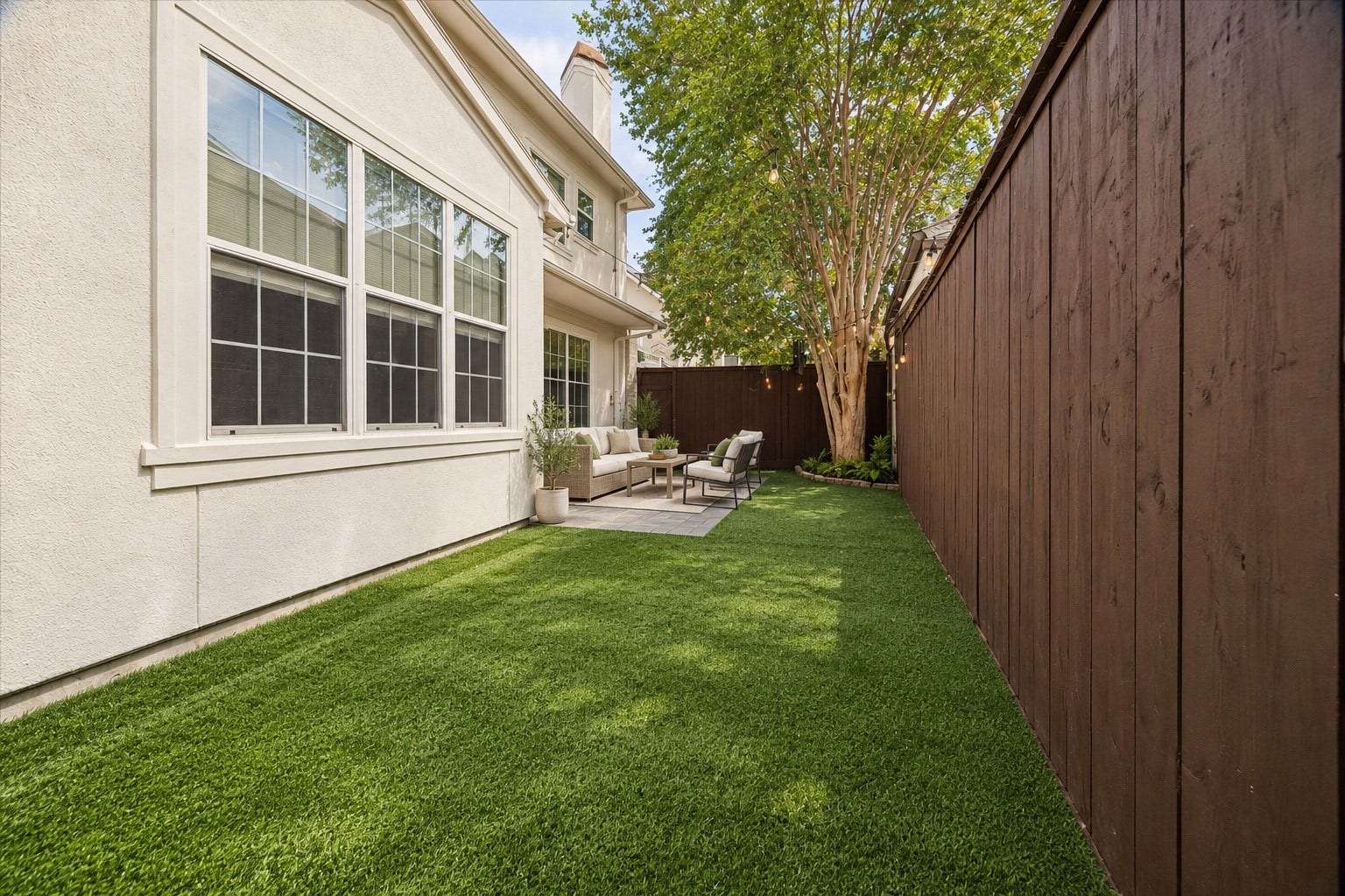1311 N Jordan Cove, Houston, TX 77055 Beautiful view highlighting the turfed green space & mature tree providing shade. The fully fenced backyard offers plenty of room for kids & pets to play, while the patio provides a separate area for outdoor dining & entertaining. A fabulous low-maintenance outdoor retreat! (Photo virtually enhanced/furnishings virtually staged).