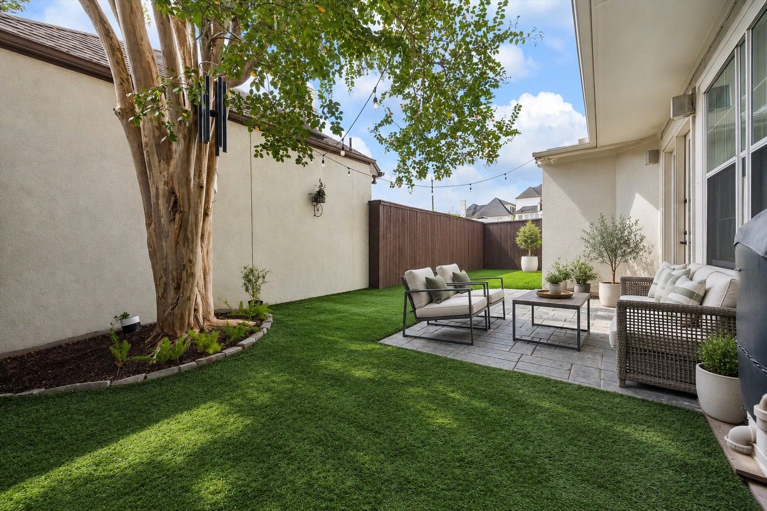 1311 N Jordan Cove, Houston, TX 77055 A sneak peak of the wonderful private backyard offering a lovely extension of the home's living spaces! Spacious patio provides ample room for outdoor furnishings & entertaining, while low-maintenance turfed green space creates a beautiful setting for pets, play & everyday enjoyment. Fully fenced w/ mature landscaping providing shade. (Photo virtually enhanced/furnishings virtually staged).
