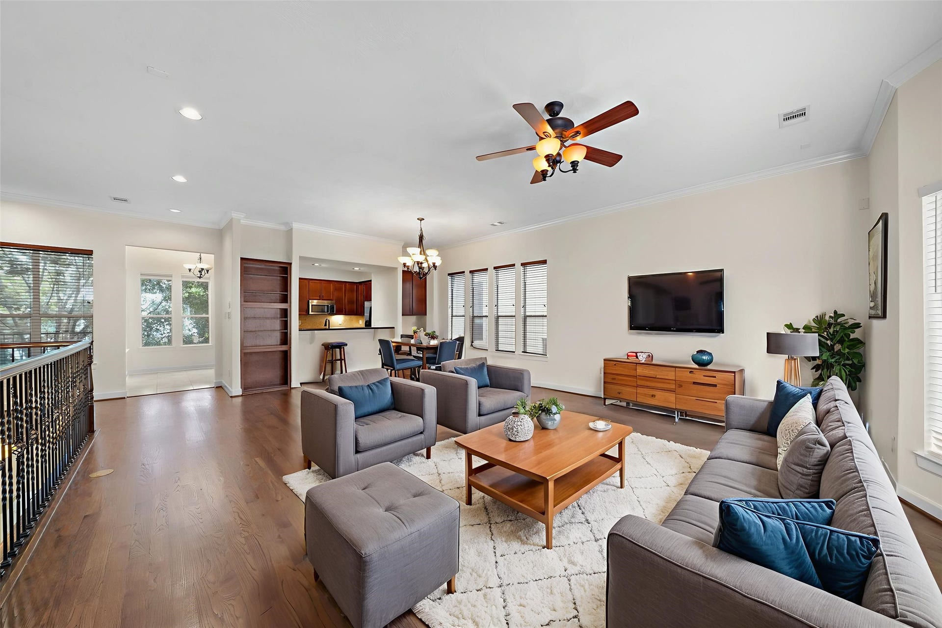 1717 Francis Street, Houston, TX 77004 Virtually Staged: The open floor plan smoothly connects the dining and living areas. It includes crown molding details, a ceiling fan, hardwood floors, windows with privacy blinds, and recessed lighting.