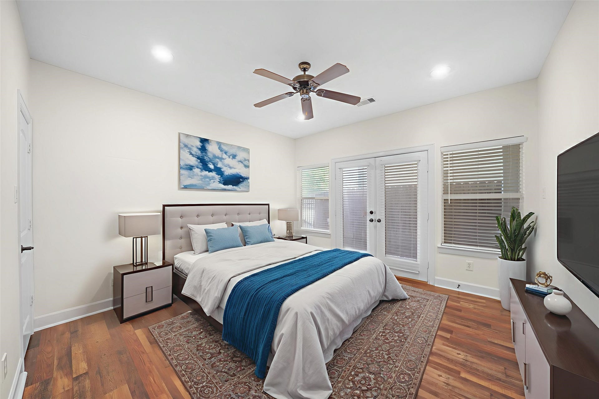 1717 Francis Street, Houston, TX 77004 Virtually Staged: Secondary bedroom located on the first floor. It features hardwood floors, windows with privacy blinds, a ceiling fan, and a double glass door with immediate access to the backyard.