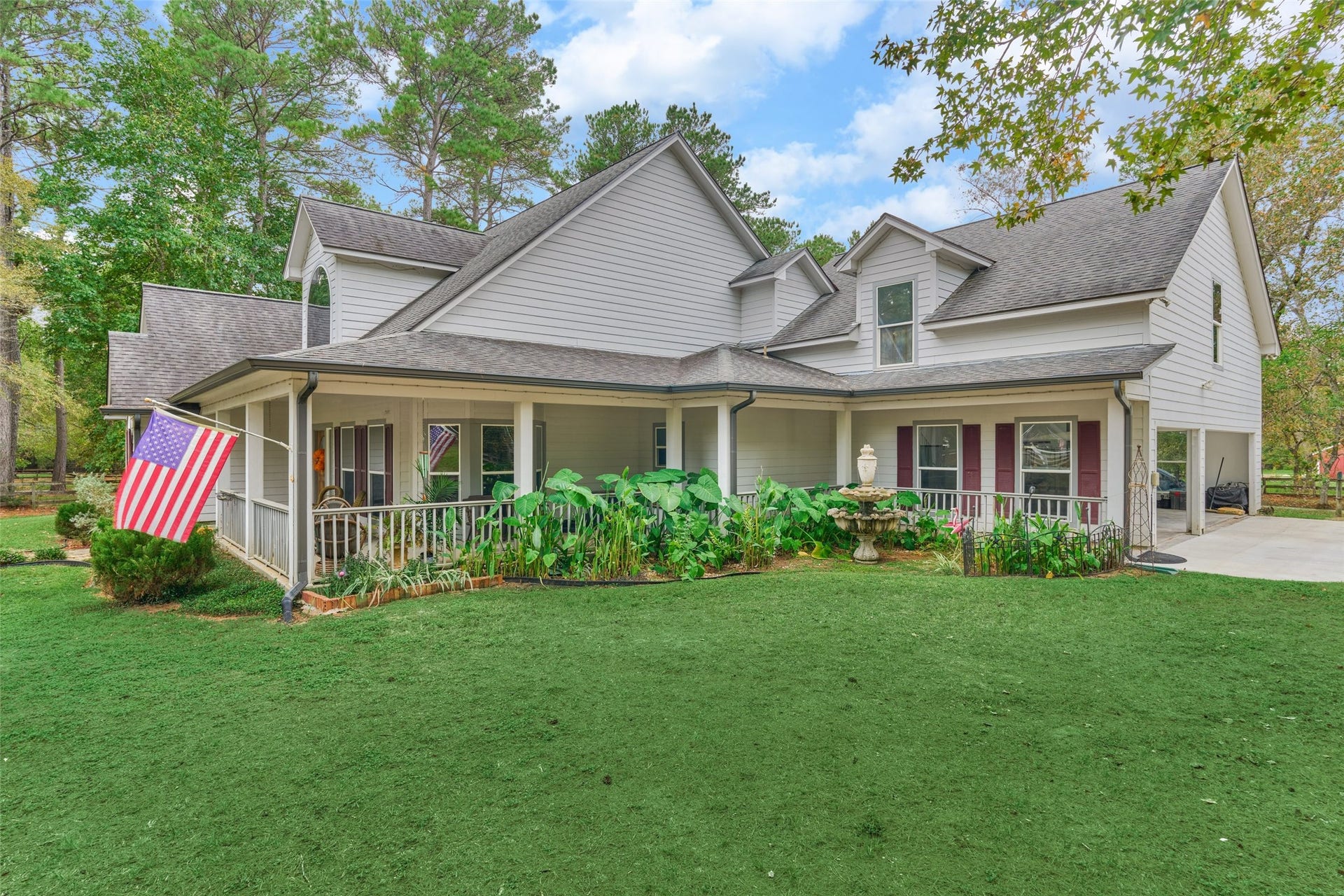 28911 Sapphire Circle, Magnolia, TX 77355 Side view of the large wrap around porch with great landscaping and fountain.