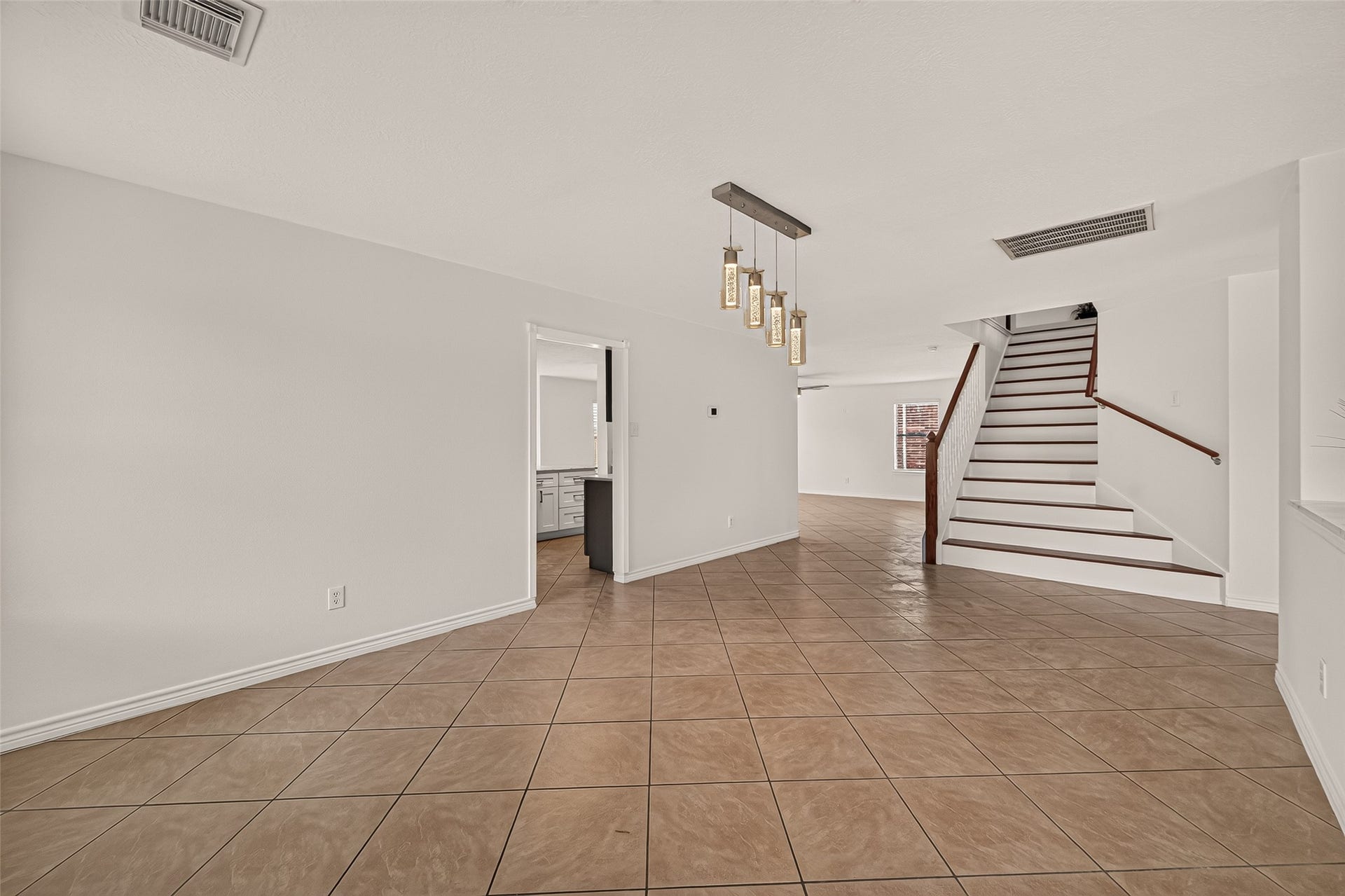 3111 Lantern Bay Lane, Katy, TX 77449 From the dining room, the open layout flows toward the living area, while the pendant lights and staircase add character to the space.