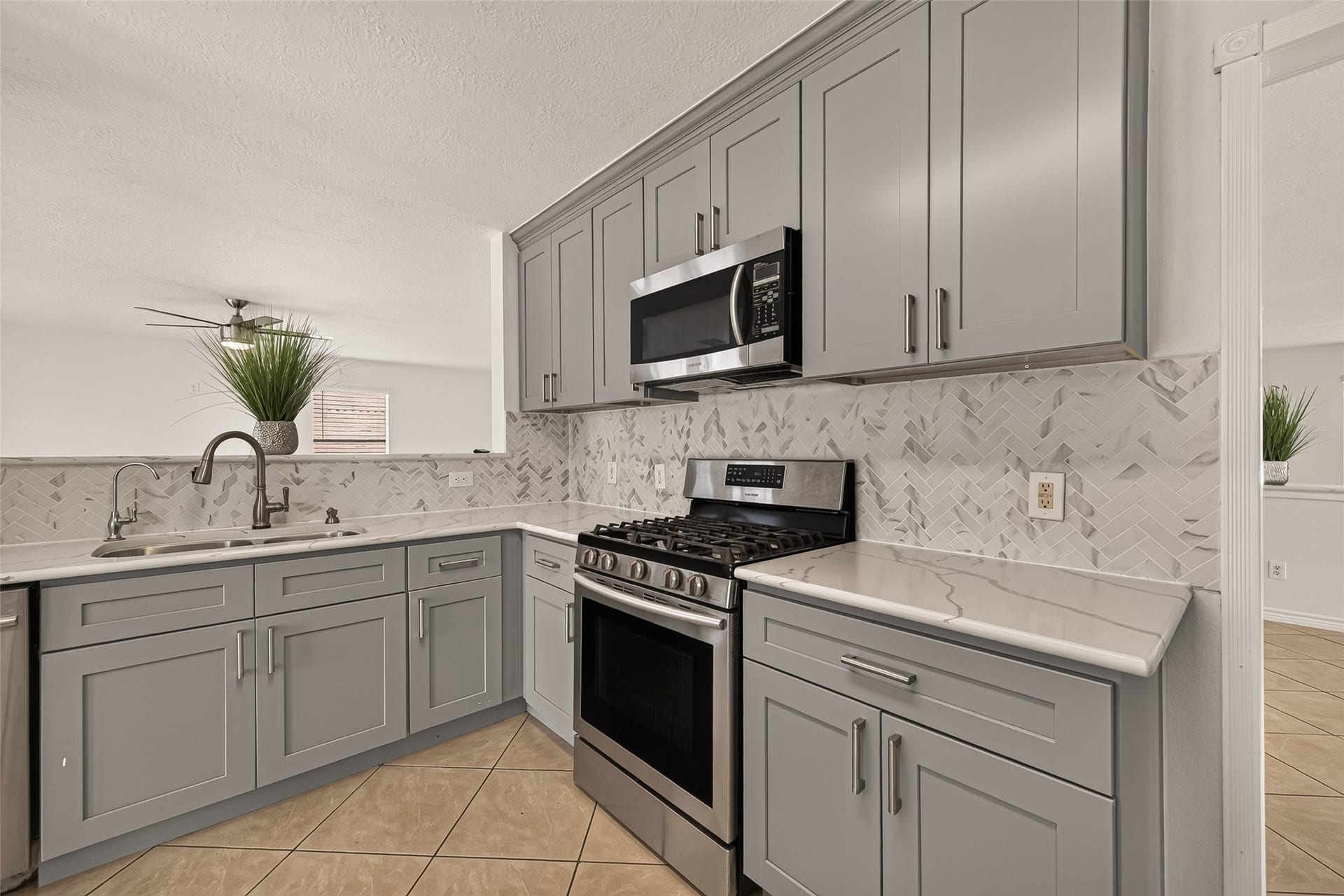 3111 Lantern Bay Lane, Katy, TX 77449 A closer look at the kitchen highlights the gray shaker cabinets, patterned tile backsplash, stainless steel gas range, and generous counter space.