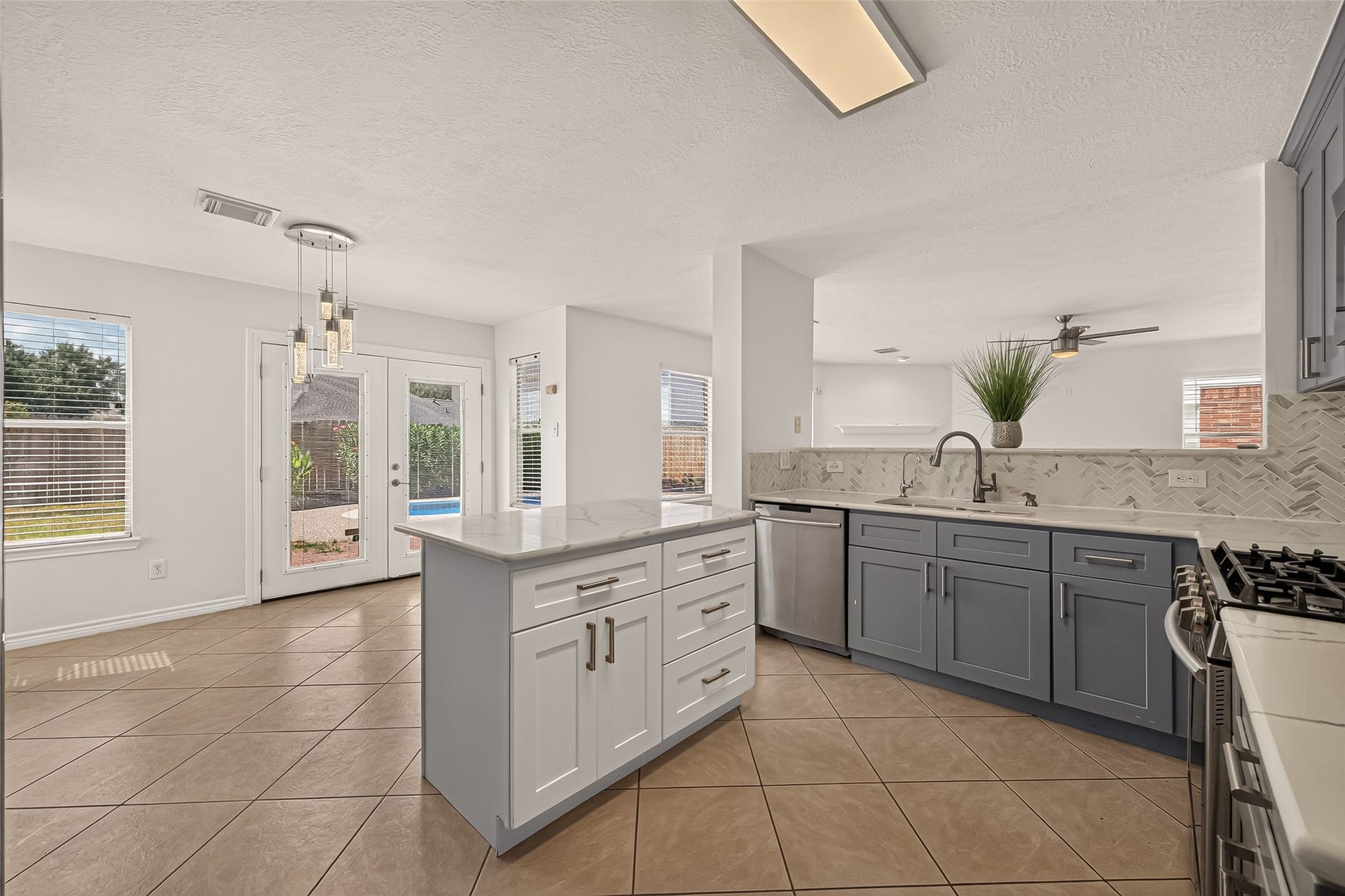 3111 Lantern Bay Lane, Katy, TX 77449 The kitchen brings everyone together with a generous island, two-tone cabinetry, and a view into the family room. French doors nearby open toward the pool for easy indoor-outdoor entertaining.
