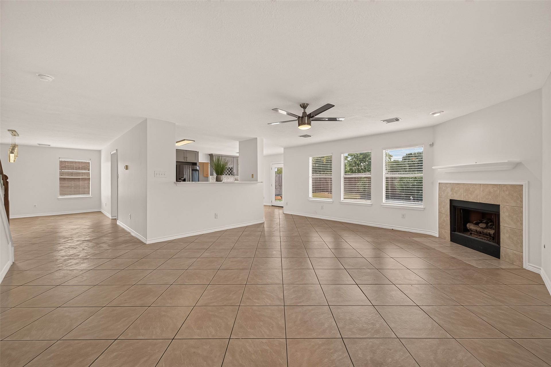 3111 Lantern Bay Lane, Katy, TX 77449 A wide view of the main floor shows how the dining area, kitchen, and family room connect, with a breakfast bar overlooking the fireplace and backyard windows.