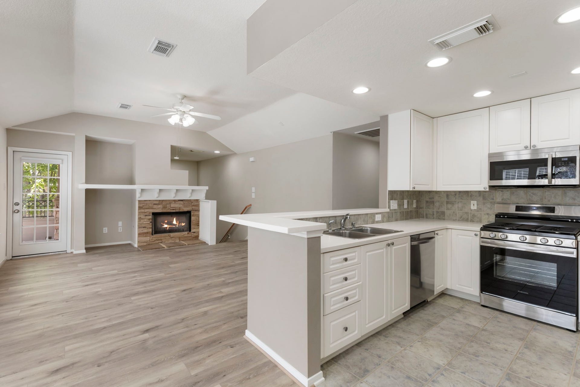 Stainless steel appliances including refrigerator and a gas range.