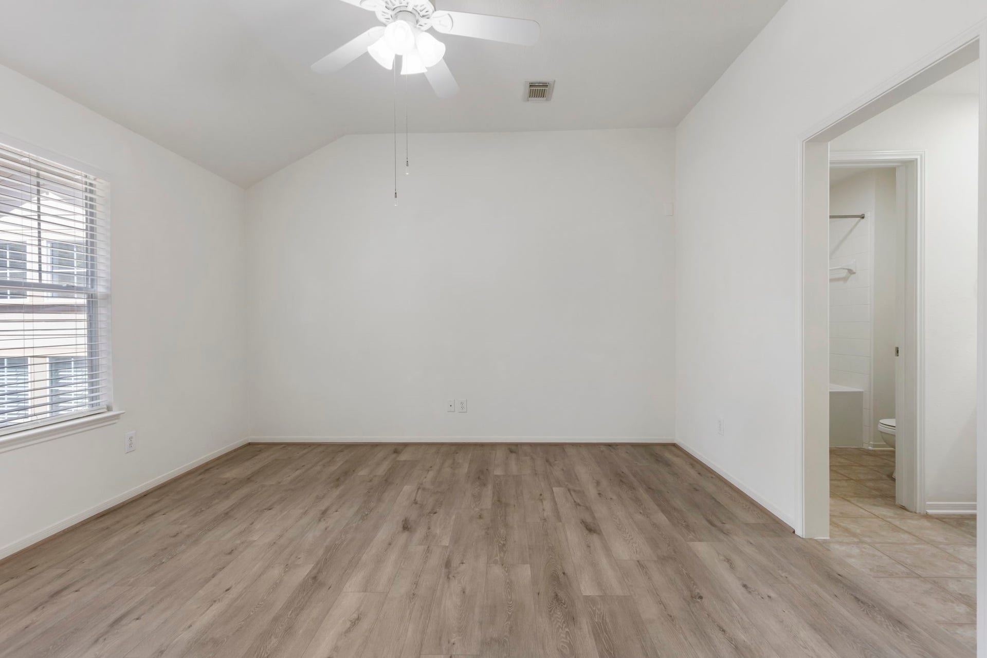 Primary bedroom with ensuite bath, spacious closet, and ceiling fan.