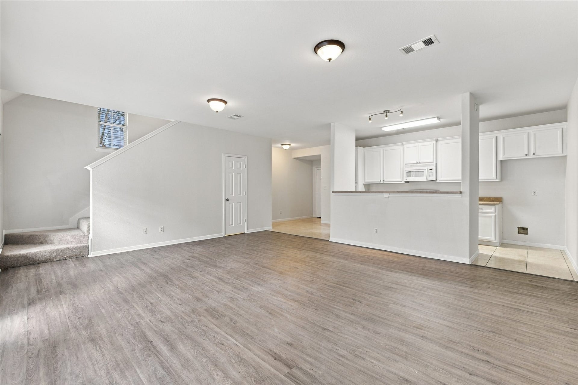 from the family room, stairs and banister on the left, full door is half bath, middle background is the front door, right is the kitchen