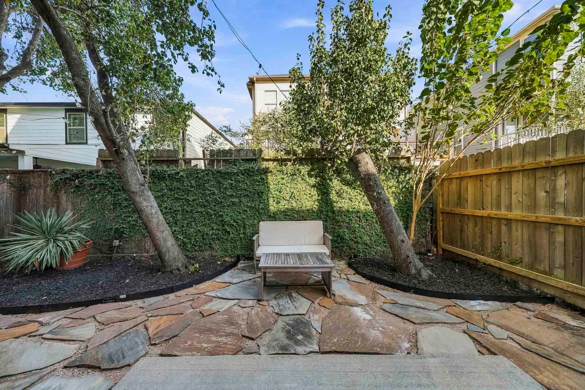 910 Malone Street, #106, Houston, TX 77007 Surrounded by mature trees, this private side patio offers a charming outdoor setting for al fresco dining, weekend gatherings or peaceful moments beneath the canopy of shade.