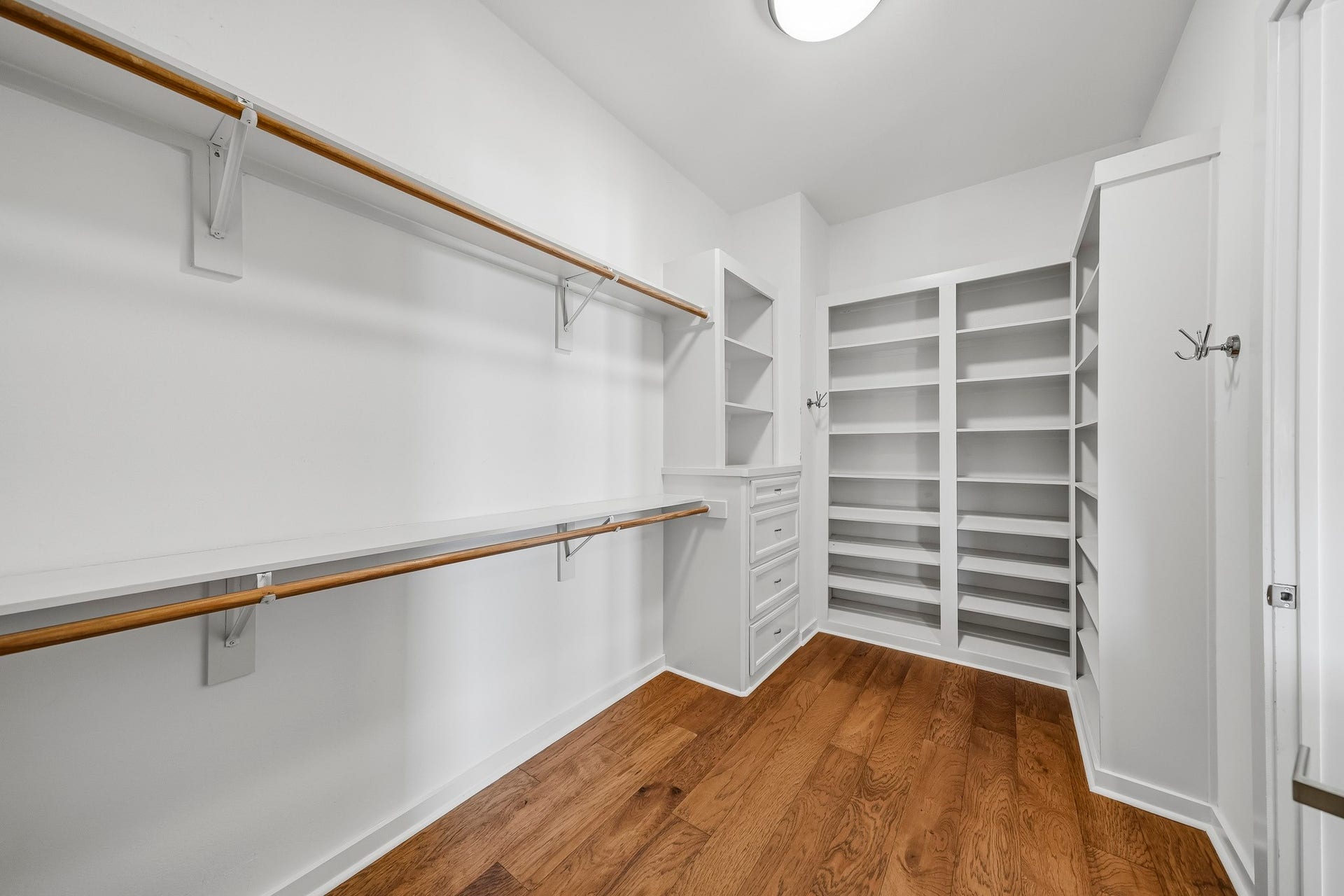 910 Malone Street, #106, Houston, TX 77007 The spacious primary closet offers exceptional wardrobe storage with built-in shelving, convenient drawers, and dual hanging rods with additional shelf space, creating a beautifully organized setting for clothing, shoes, and accessories.