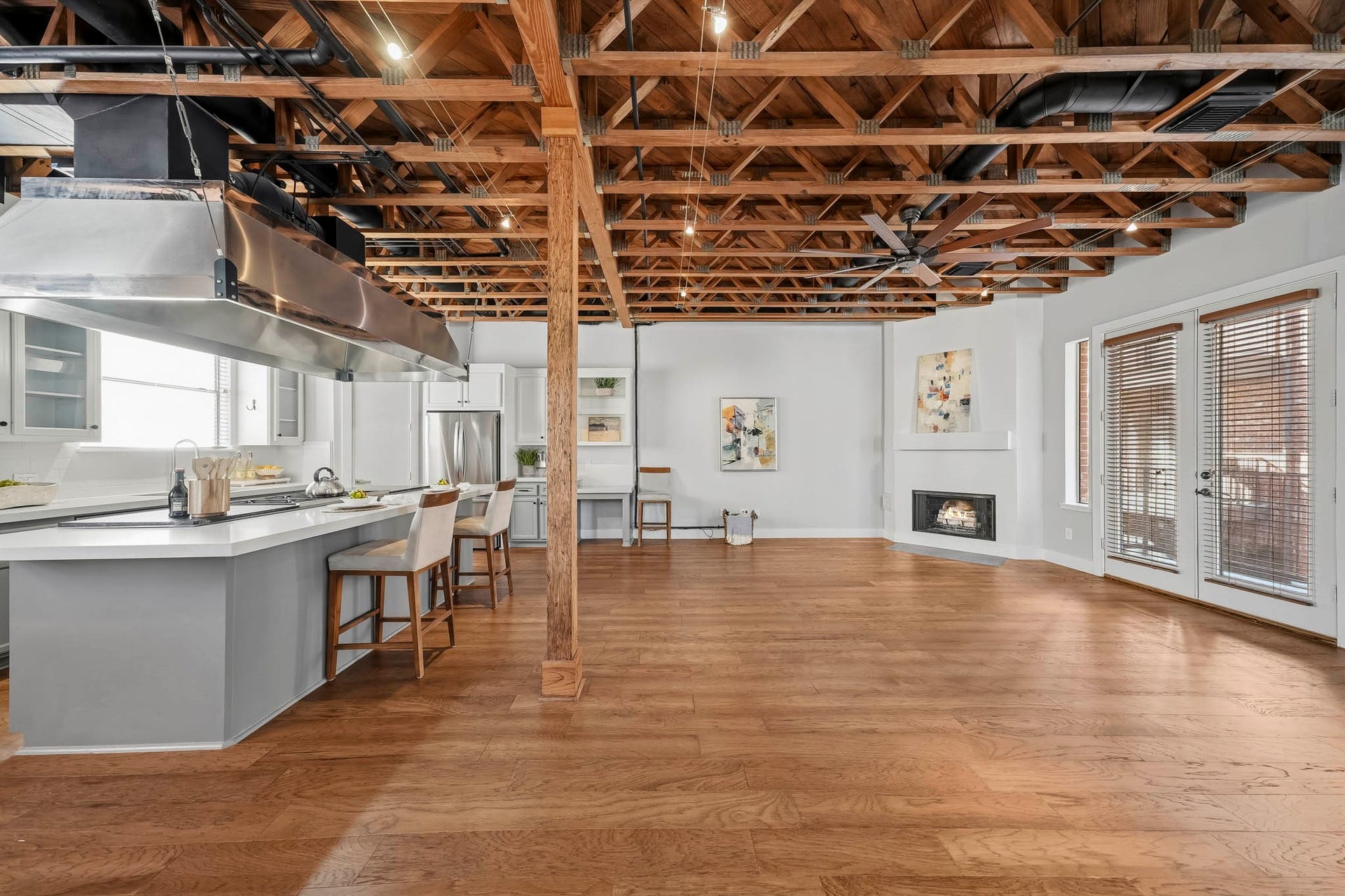 910 Malone Street, #106, Houston, TX 77007 The second-floor family room offers a warm and sophisticated gathering space, featuring rich hardwood floors installed in 2023, architectural exposed beams and distinctive wood trusses that lend timeless character. Track lighting, integrated speakers and a ceiling fan complete this inviting space, blending architectural charm with modern comfort.