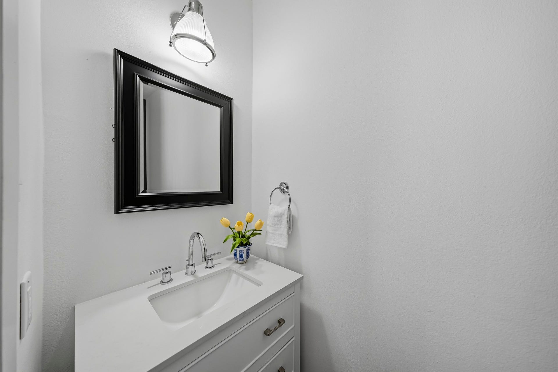 910 Malone Street, #106, Houston, TX 77007 The elegantly appointed powder room features rich hardwood floors, a furniture-style vanity installed in 2023 and topped with a Quartz counter and a distinctive wood beadboard accent wall that adds warmth and architectural character.