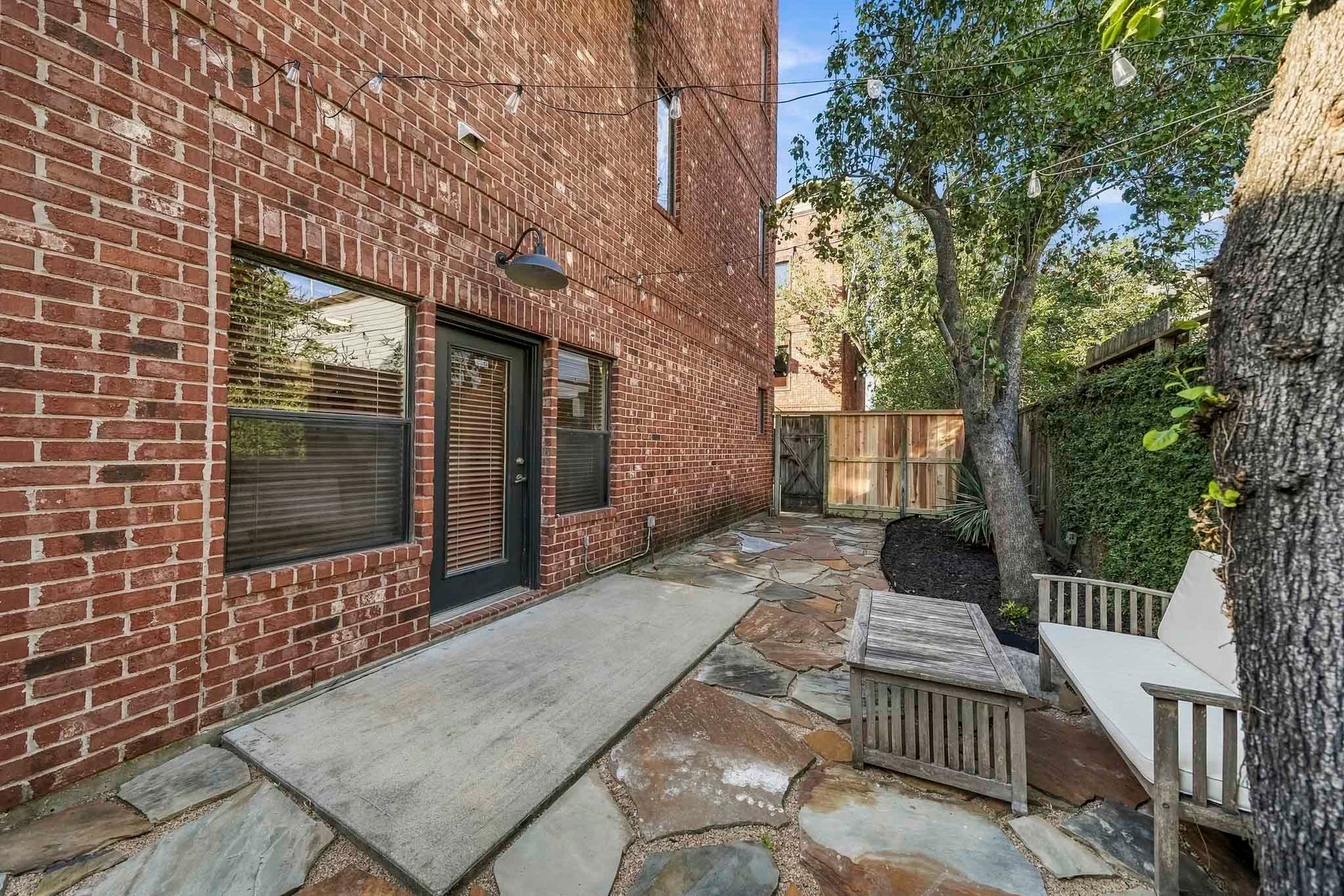 910 Malone Street, #106, Houston, TX 77007 A private side patio features a concrete surface framed by flagstone pavers, creating a charming outdoor space to enjoy fresh air and relaxation.