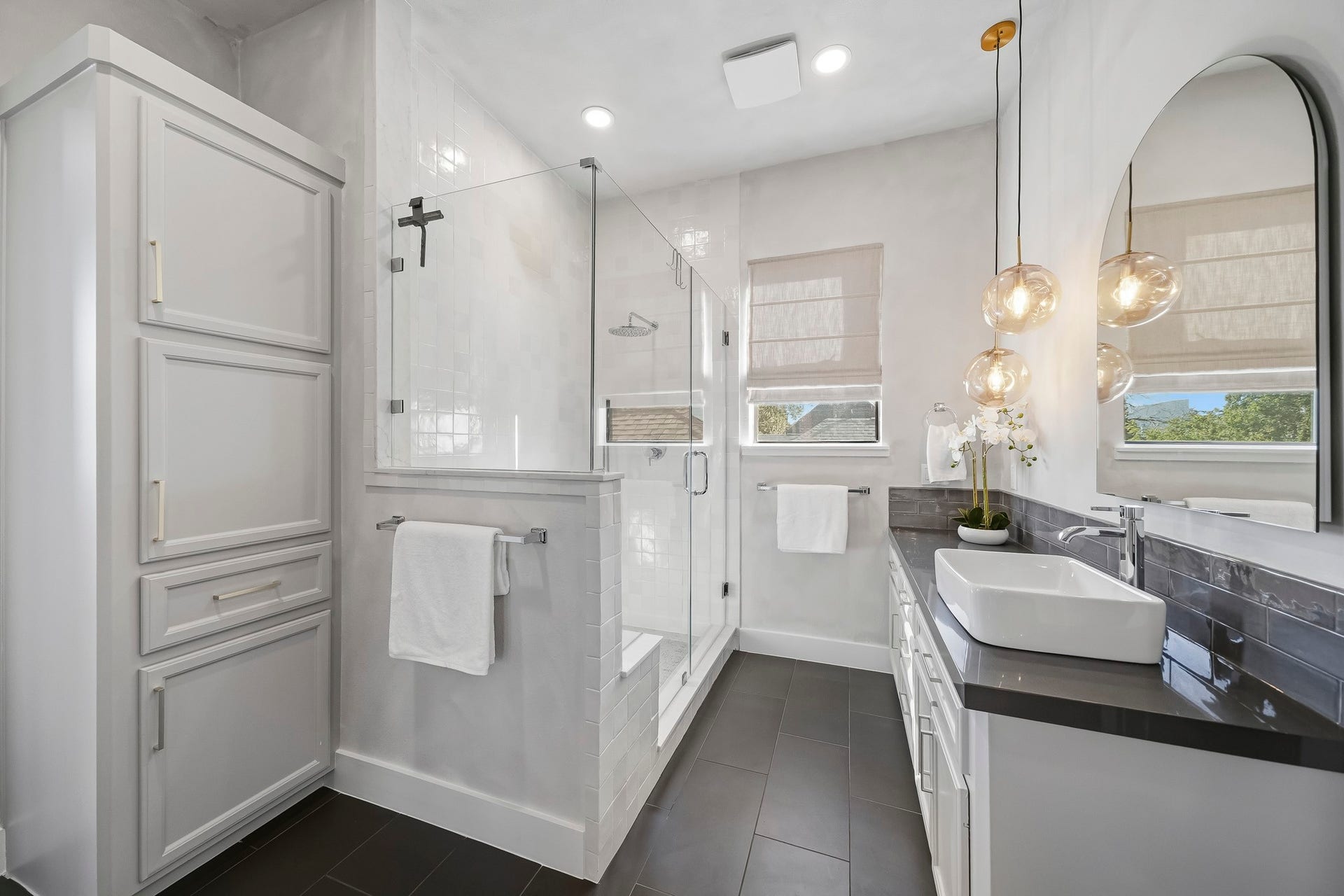 910 Malone Street, #106, Houston, TX 77007 The luxurious walk-in shower features a sleek frameless glass entry, floor-to-ceiling tile surround, a rainfall showerhead and a quartz-topped bench, creating a spa-inspired experience in the comfort of your own home.