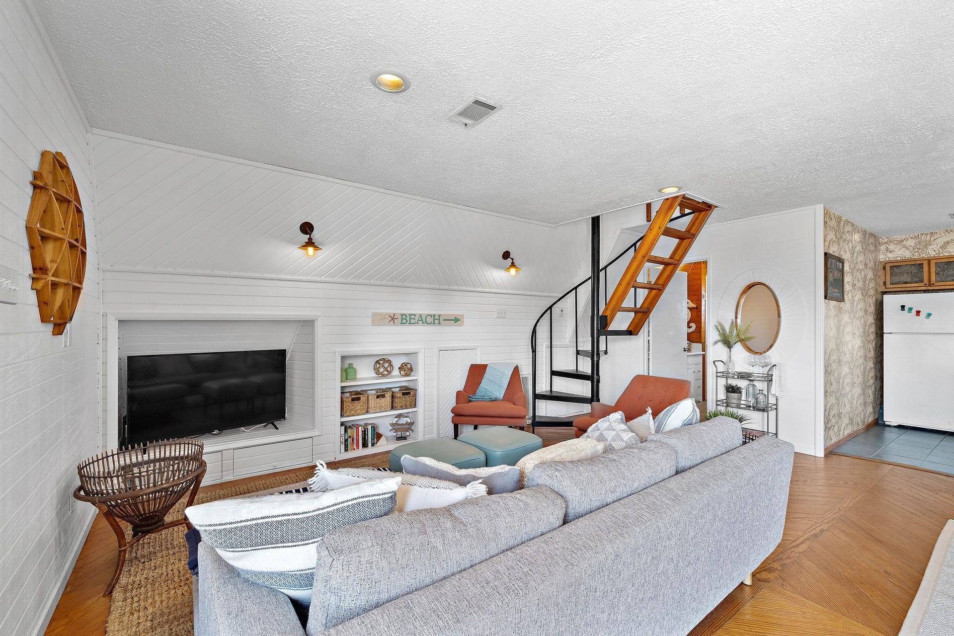 16610 Nassau Way, Galveston, TX 77554 Charming living room with cozy seating, a spiral staircase, and built-in shelving, perfect for relaxing and entertaining.