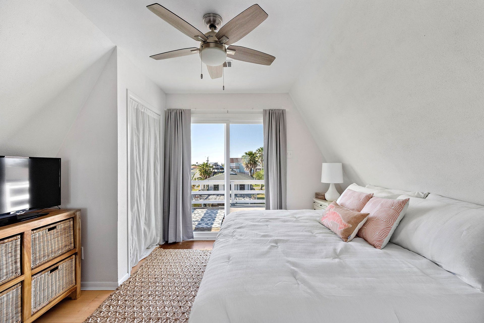 16610 Nassau Way, Galveston, TX 77554 Bright and airy bedroom with a king-sized bed, ceiling fan, and sliding glass doors leading to a private balcony, offering serene views.