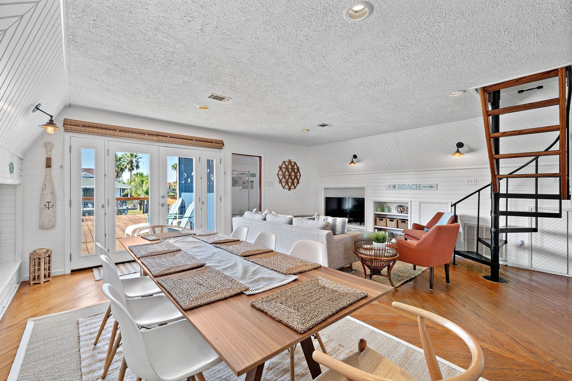 16610 Nassau Way, Galveston, TX 77554 Bright and inviting open-concept living area with a seamless flow from the dining space to a cozy lounge, featuring large French doors that open to a sunlit deck.