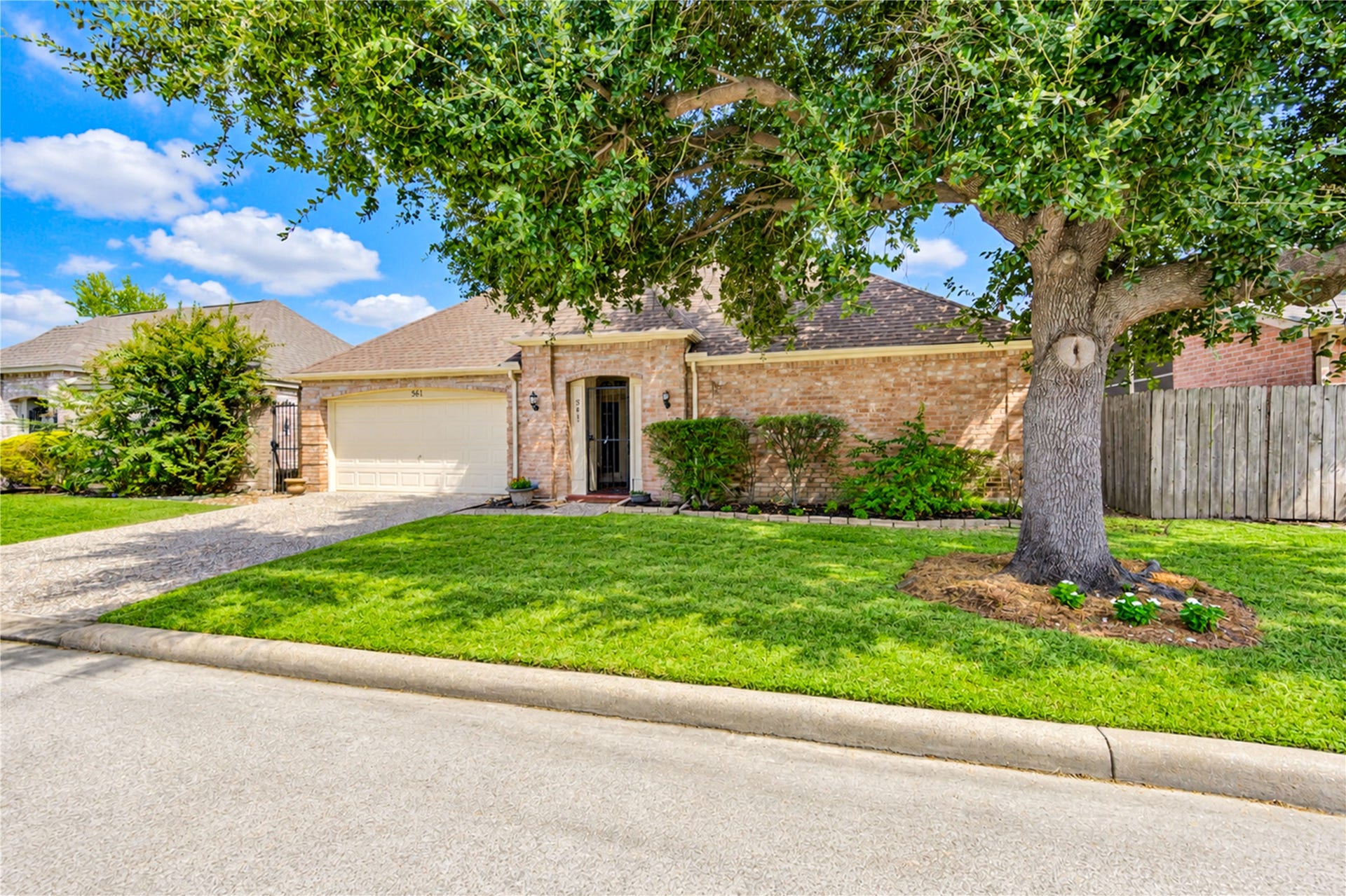 361 Champions Colony III, Houston, TX 77069 Charming brick home with a spacious front yard and mature tree, offering a welcoming entrance and attached two-car garage.