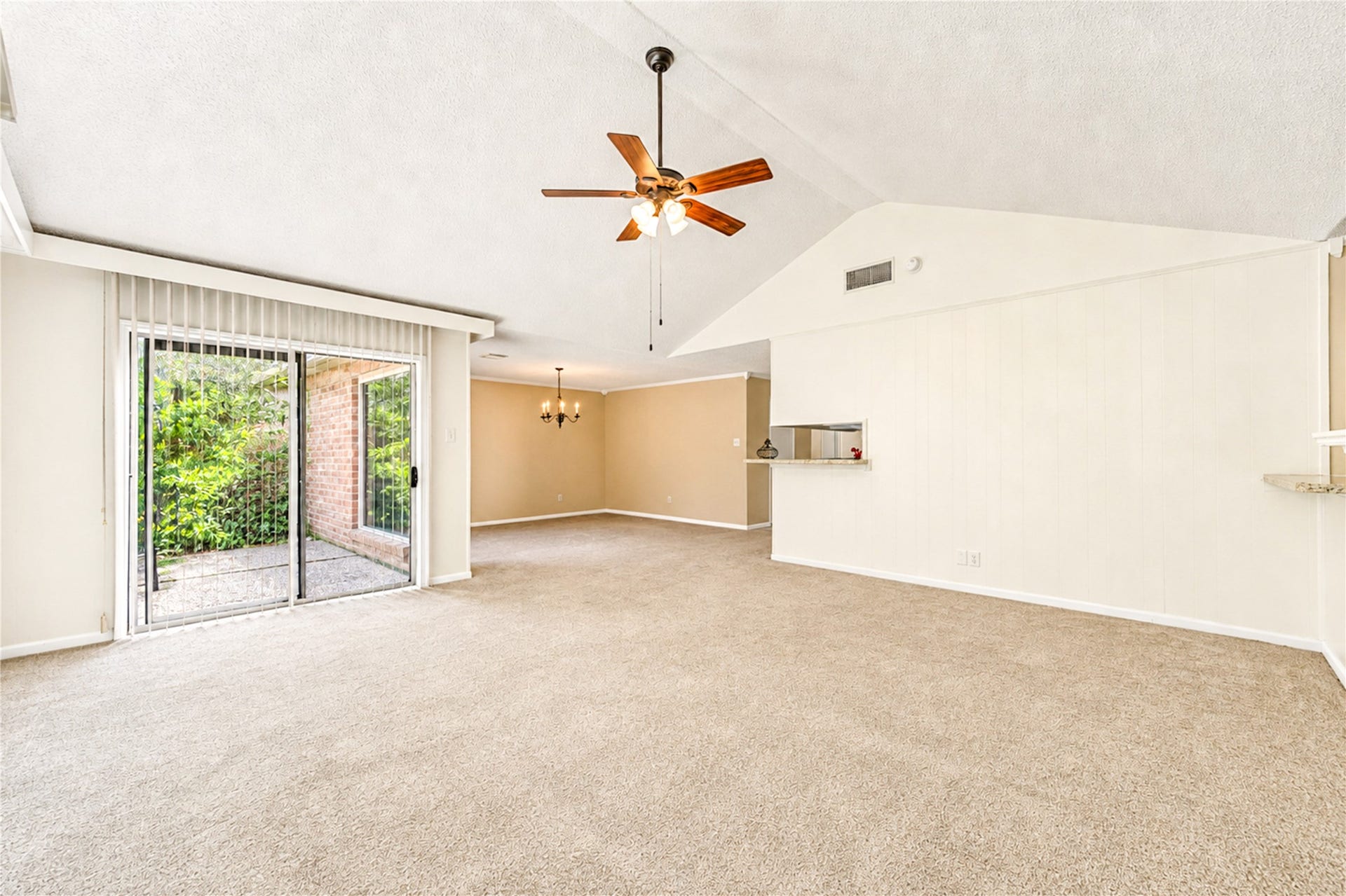 361 Champions Colony III, Houston, TX 77069 Spacious living area with vaulted ceilings, featuring a ceiling fan and abundant natural light from sliding glass doors leading to a patio.