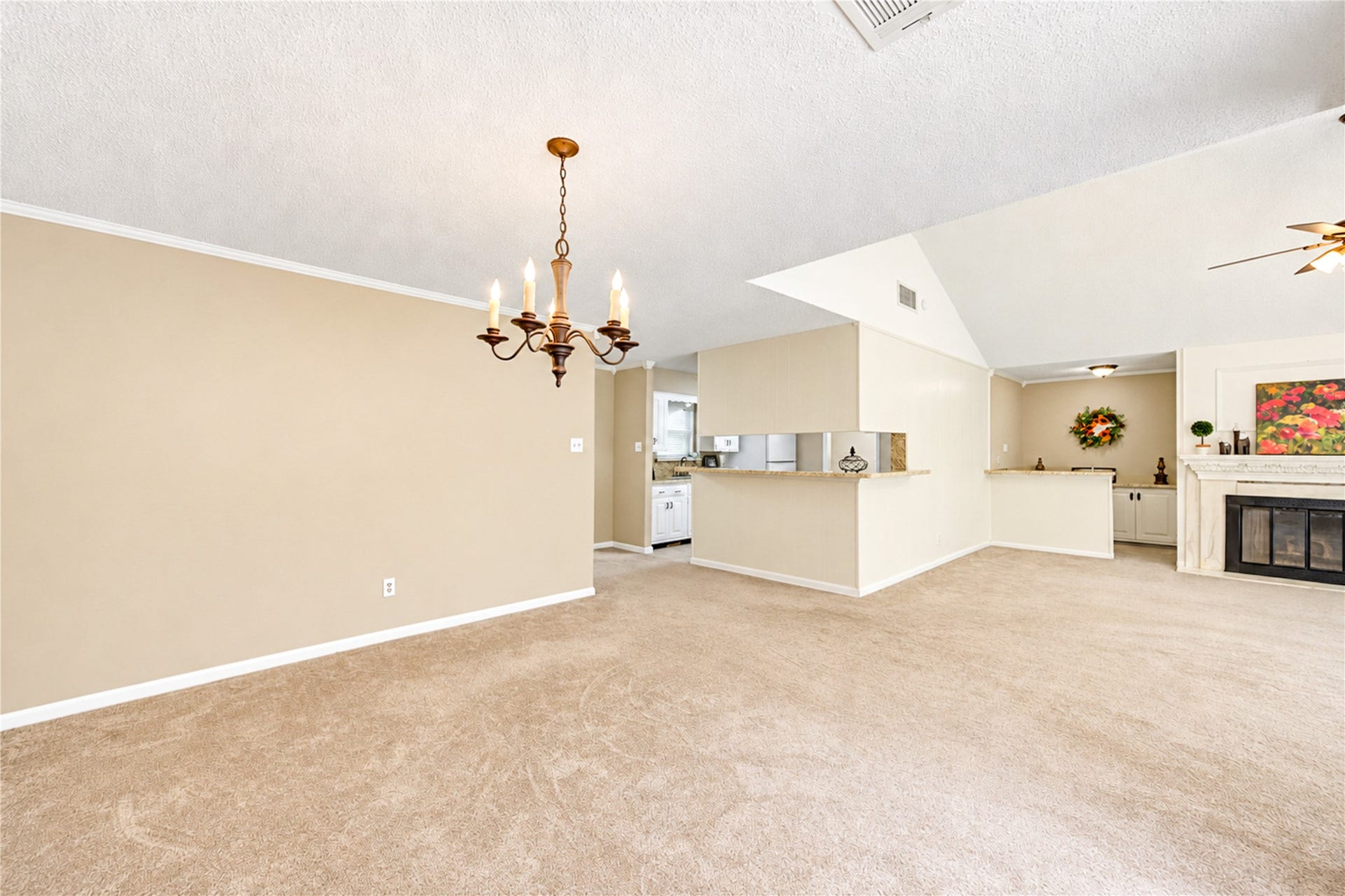 361 Champions Colony III, Houston, TX 77069 Spacious open-plan living area featuring a cozy fireplace, elegant chandelier, and neutral tones, seamlessly connecting to the kitchen and dining spaces.