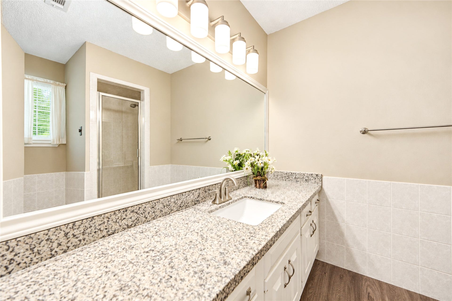 361 Champions Colony III, Houston, TX 77069 Elegant master bathroom featuring a sleek granite countertop, large mirror, and a glass-enclosed shower, complemented by warm lighting and neutral tones.