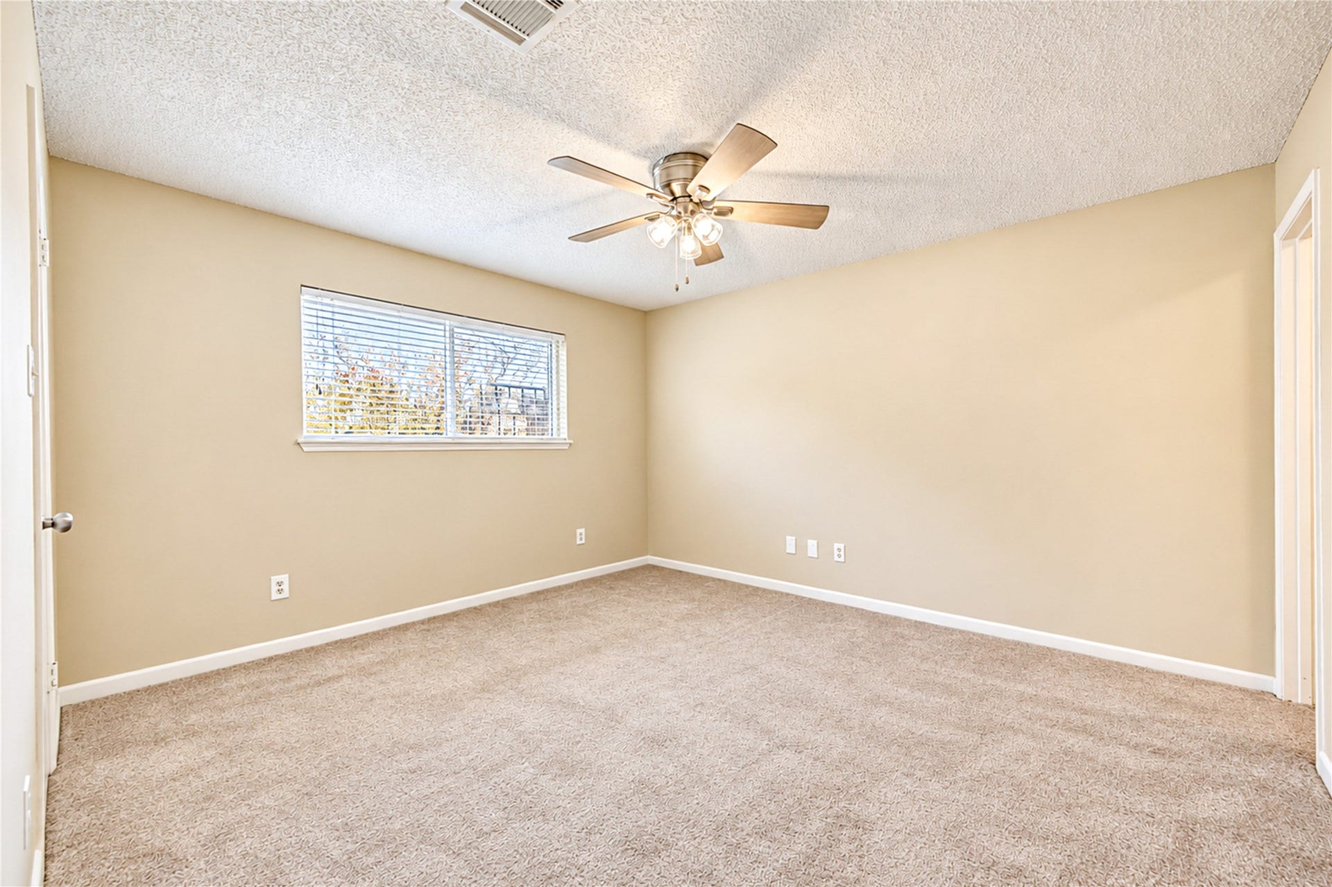 361 Champions Colony III, Houston, TX 77069 Spacious bedroom with plush carpet, neutral walls, and a large window for natural light, complemented by a stylish ceiling fan.