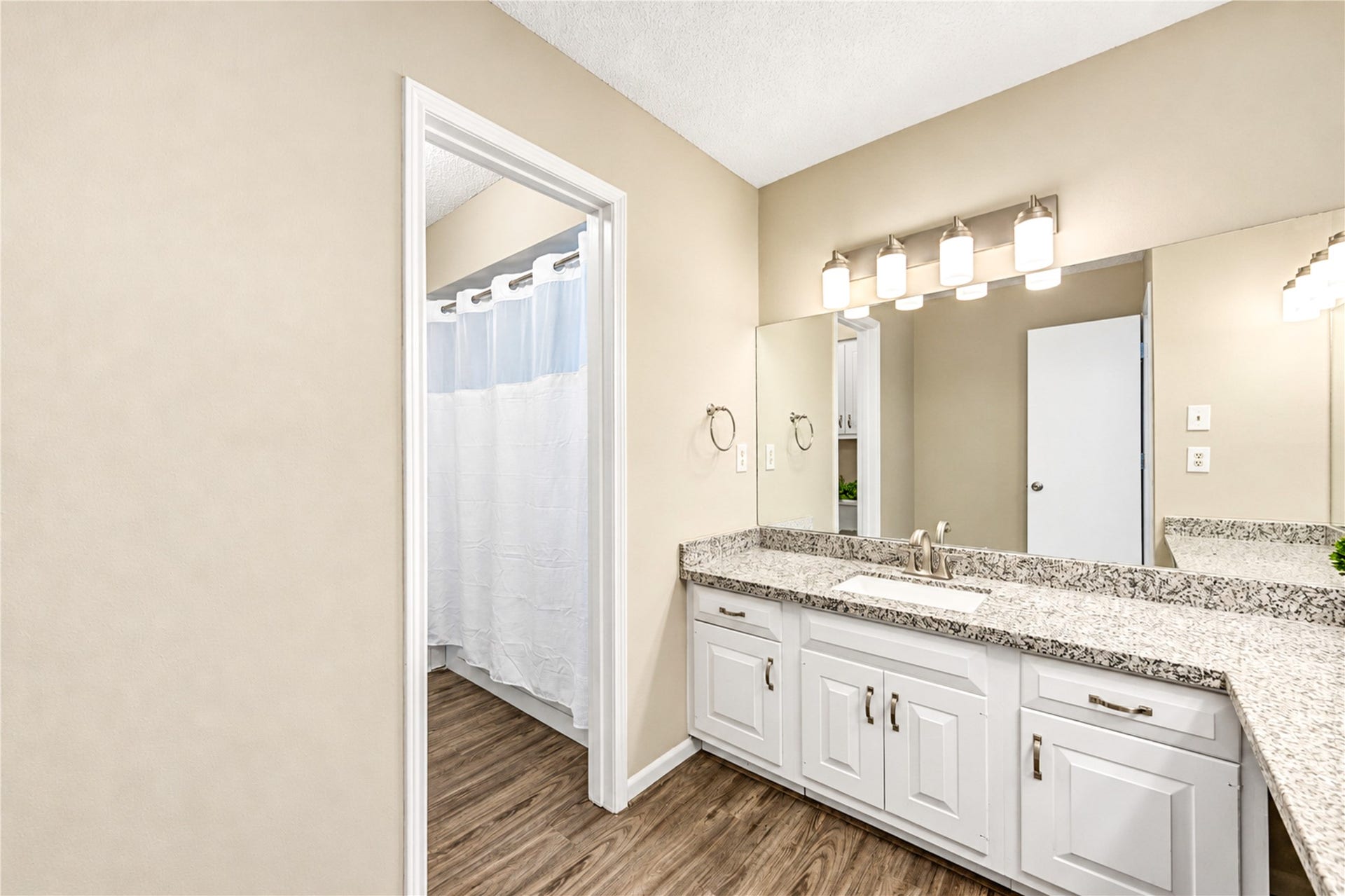 361 Champions Colony III, Houston, TX 77069 Bright and inviting bathroom featuring a stylish double vanity with granite countertops, elegant lighting, and sleek hardwood flooring.