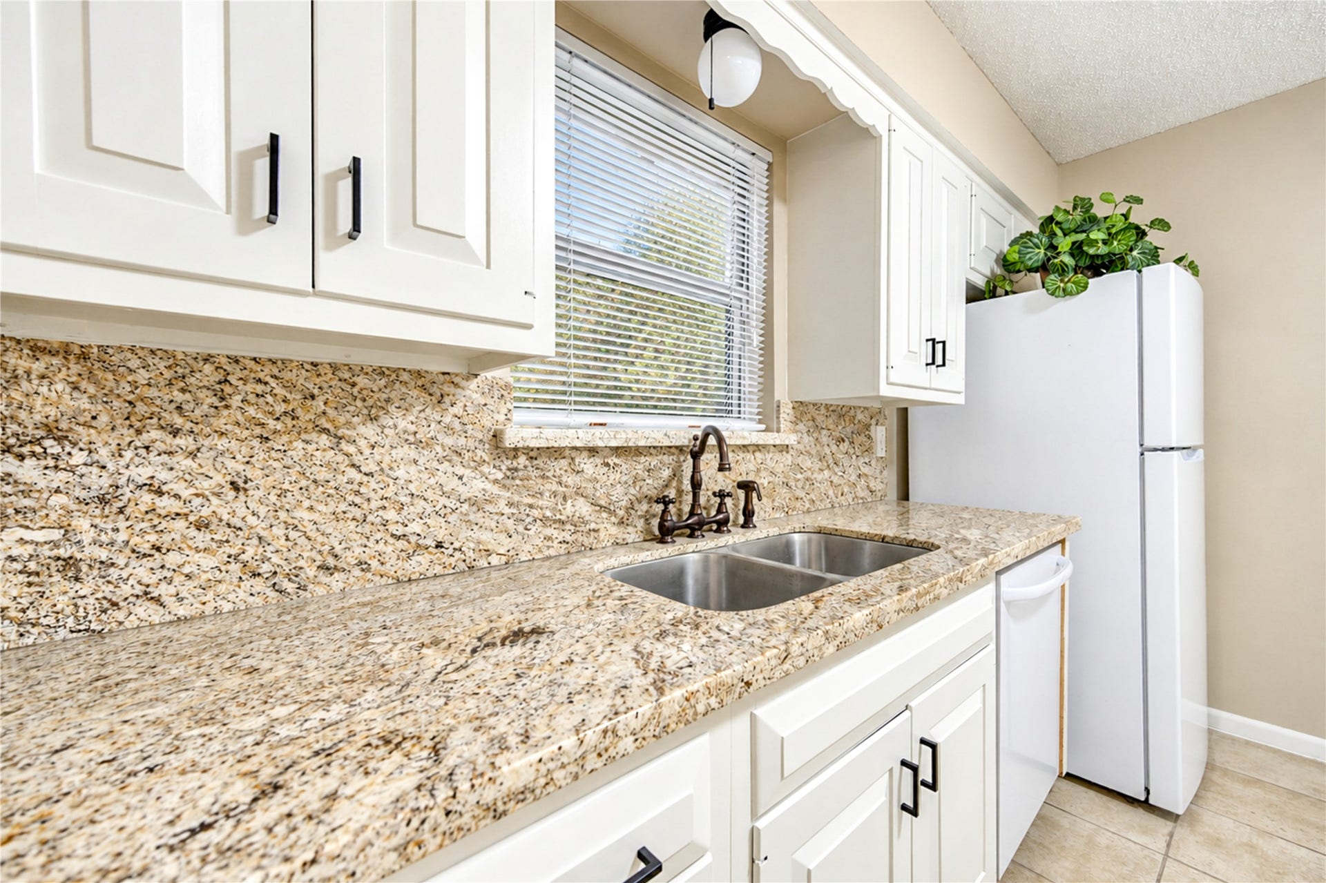 361 Champions Colony III, Houston, TX 77069 Charming kitchen with elegant granite countertops, classic white cabinetry, and a convenient double sink, complemented by natural light through a window above.