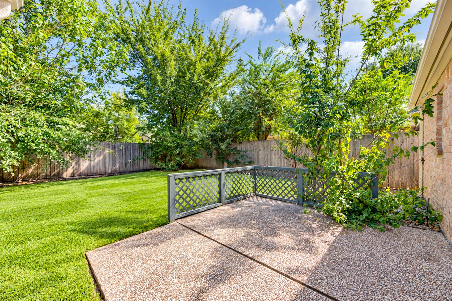 361 Champions Colony III, Houston, TX 77069 Charming backyard with lush greenery, a cozy patio area, and a privacy fence, perfect for relaxing and entertaining.