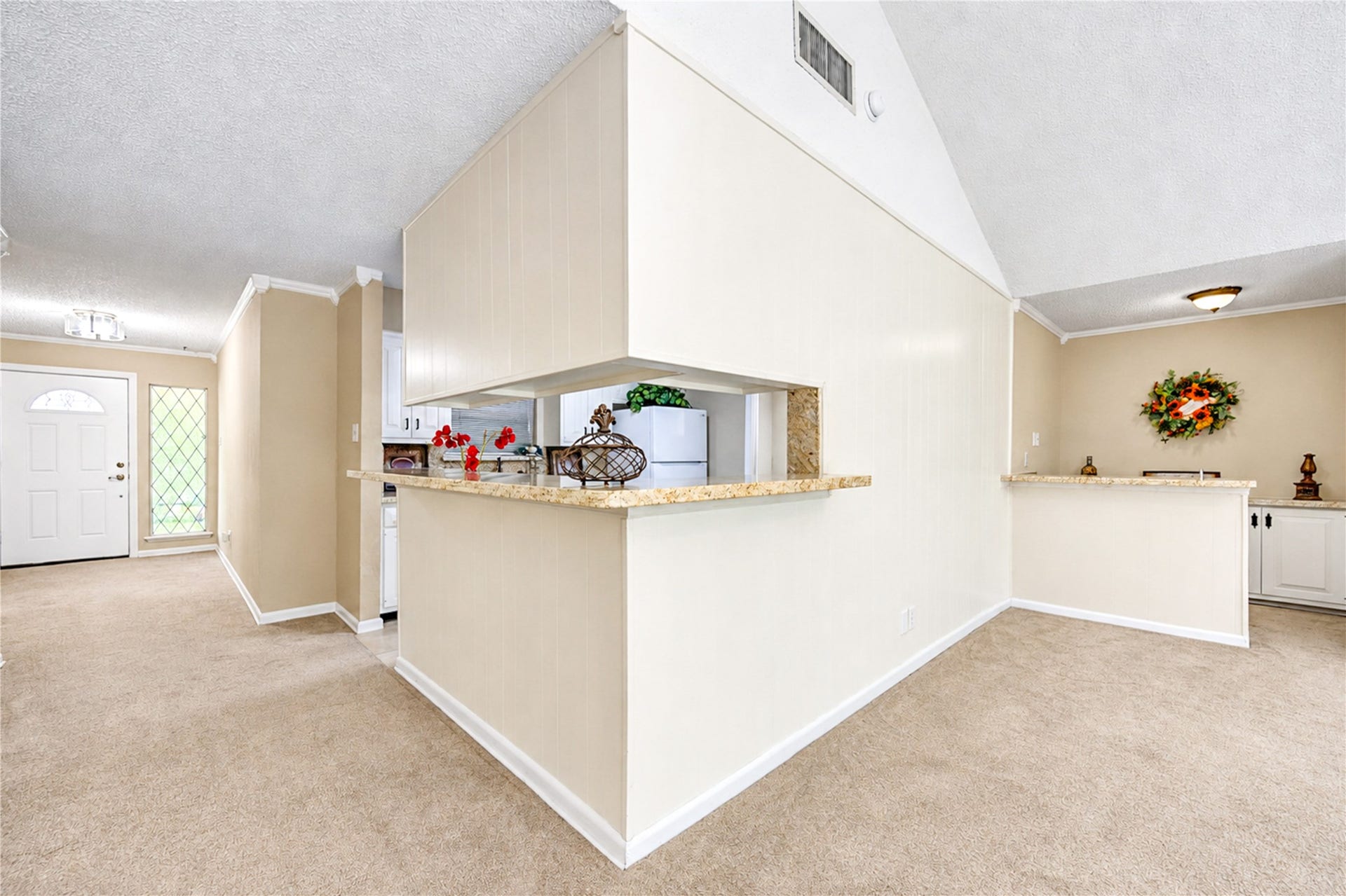 361 Champions Colony III, Houston, TX 77069 Spacious living area with neutral tones, featuring a cozy carpet, vaulted ceiling, and an open pass-through to the kitchen. The entryway is inviting with a decorative glass-panel door and ample natural light.