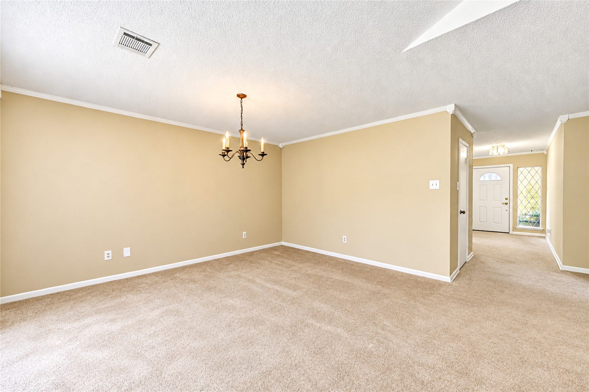 361 Champions Colony III, Houston, TX 77069 Spacious living area with plush carpeting, soft neutral tones, and elegant crown molding, enhanced by a classic chandelier and a welcoming entryway.