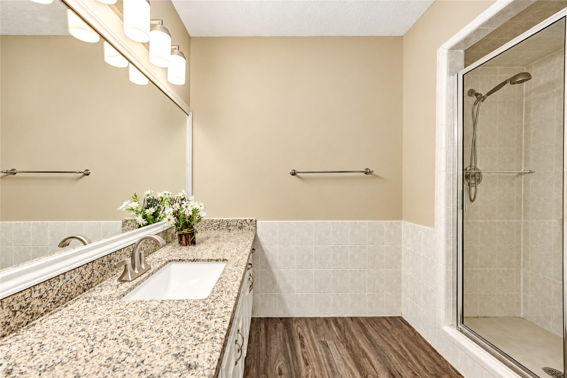 361 Champions Colony III, Houston, TX 77069 Elegant primary bedroom with ensuite and a spacious granite countertop with under mount sink, modern fixtures, and a glass-enclosed shower, complemented by warm lighting and wood-style flooring.