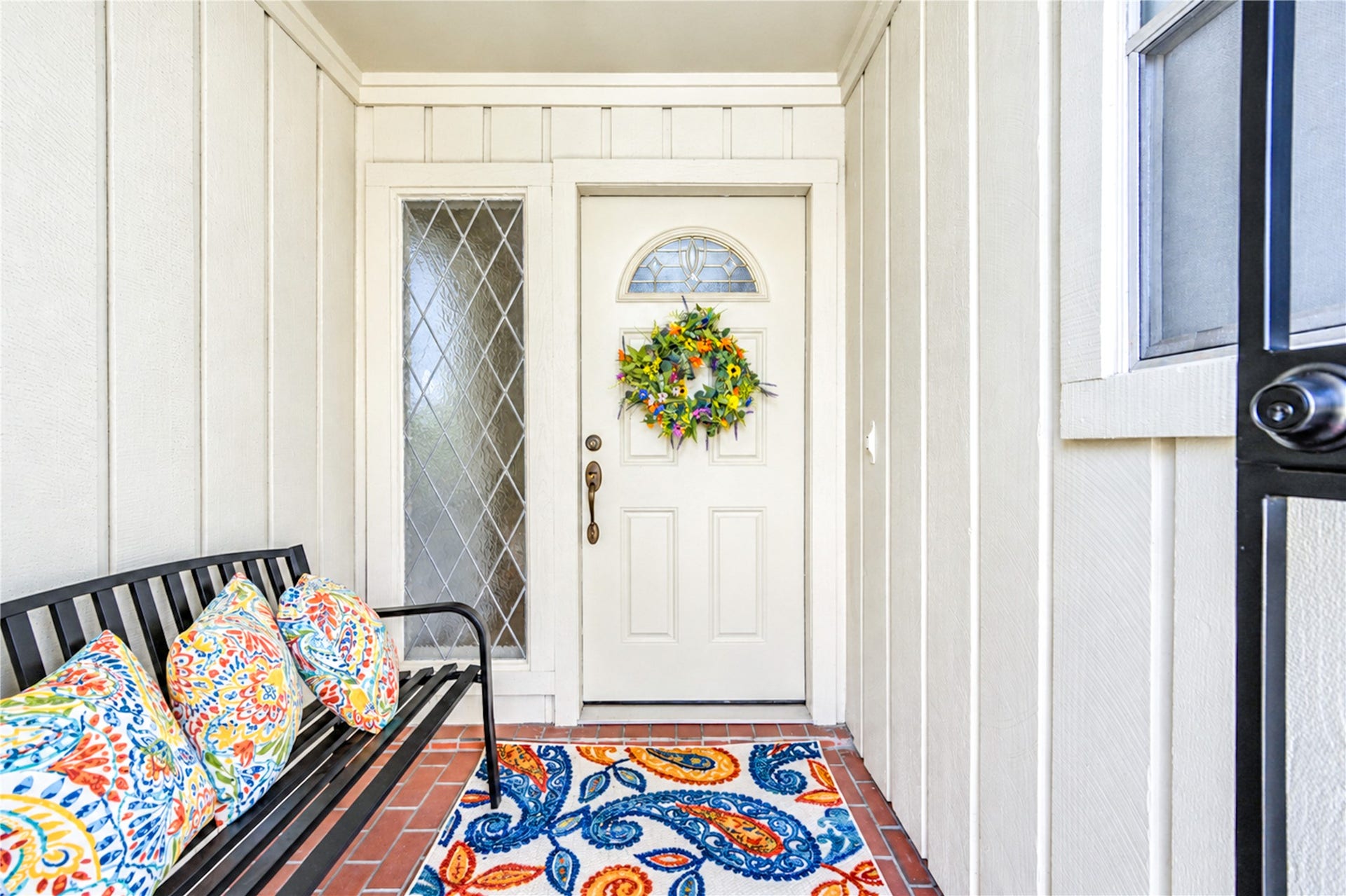 361 Champions Colony III, Houston, TX 77069 Charming entryway featuring a white door with an elegant decorative glass panel, complemented by a vibrant wreath and colorful cushions on a sleek bench.