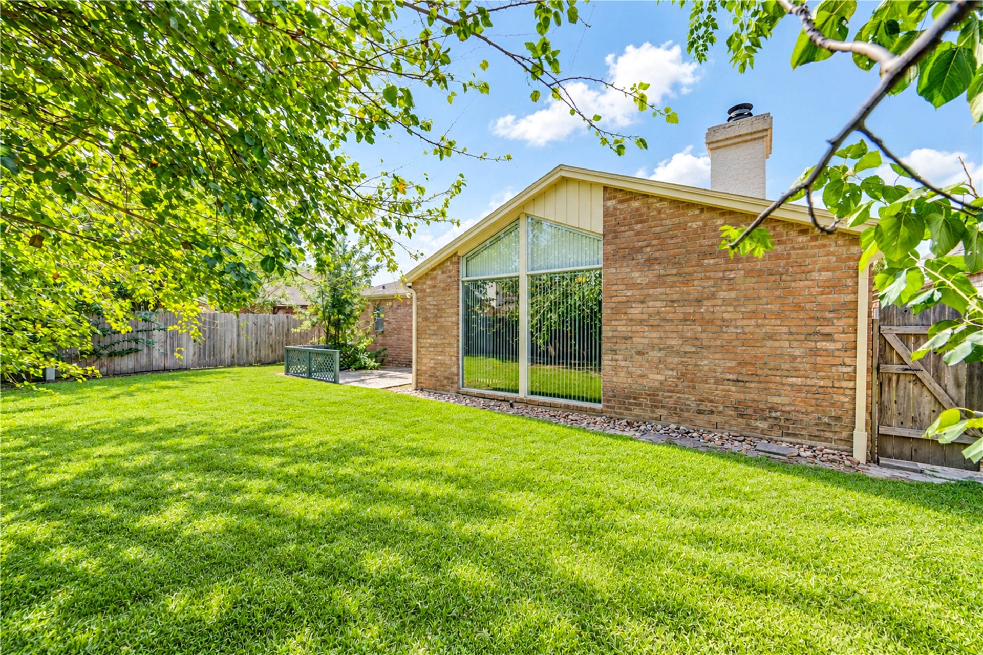 361 Champions Colony III, Houston, TX 77069 Expansive backyard with lush green lawn and a charming brick exterior, perfect for outdoor activities and relaxation.