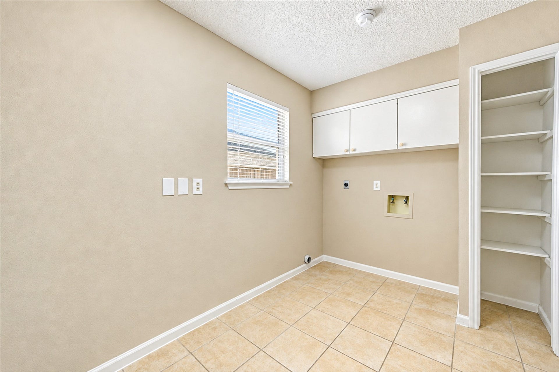 361 Champions Colony III, Houston, TX 77069 Spacious laundry room with tile flooring, built-in shelving, and ample natural light from a large window.
