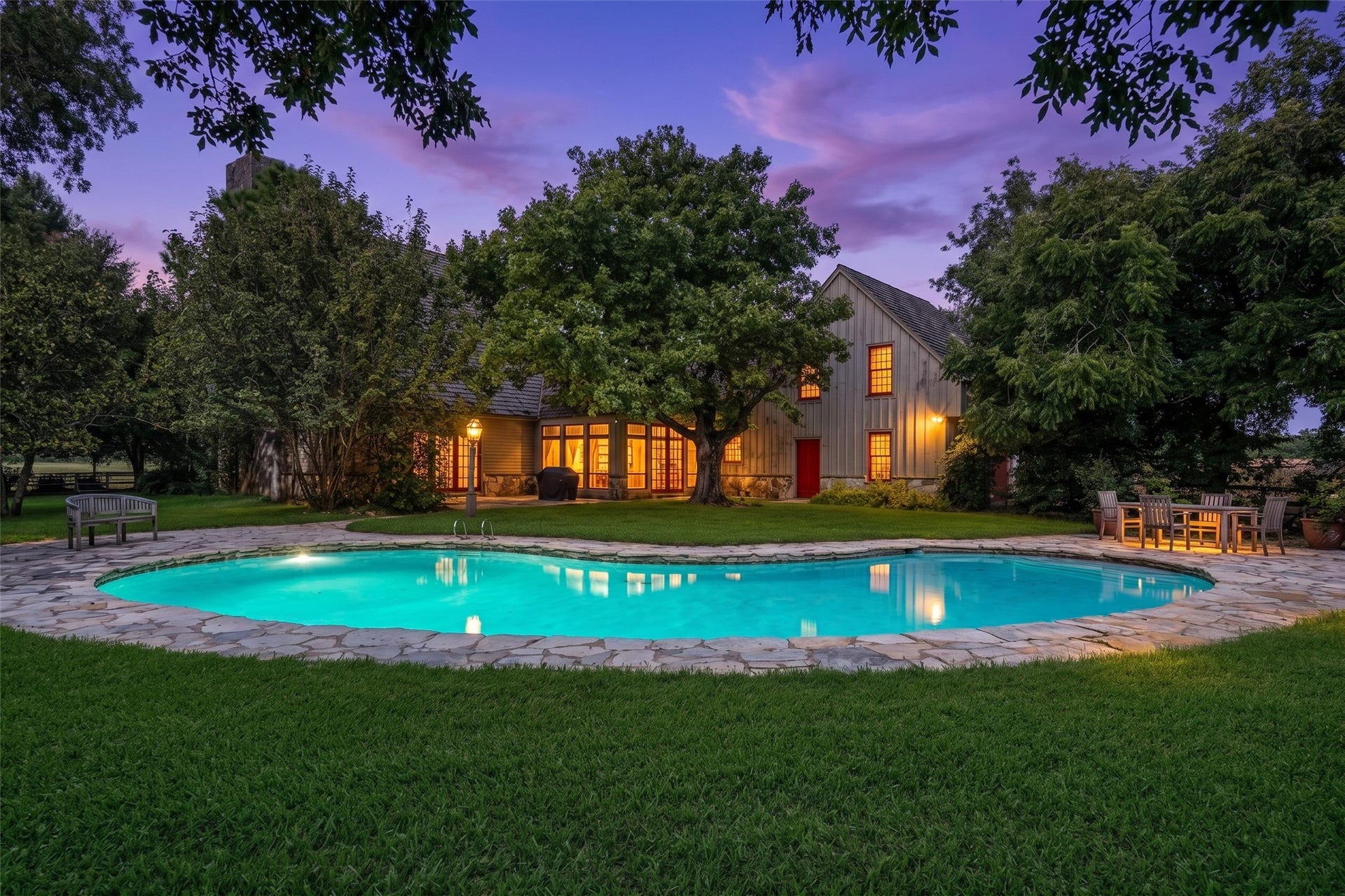 38914 Sampson Road, Brookshire, TX 77423 As the sun goes down, Saltbox Homestead takes on a magic of its own glowing windows, mature trees and a pool made for lingering evenings under the Texas sky.