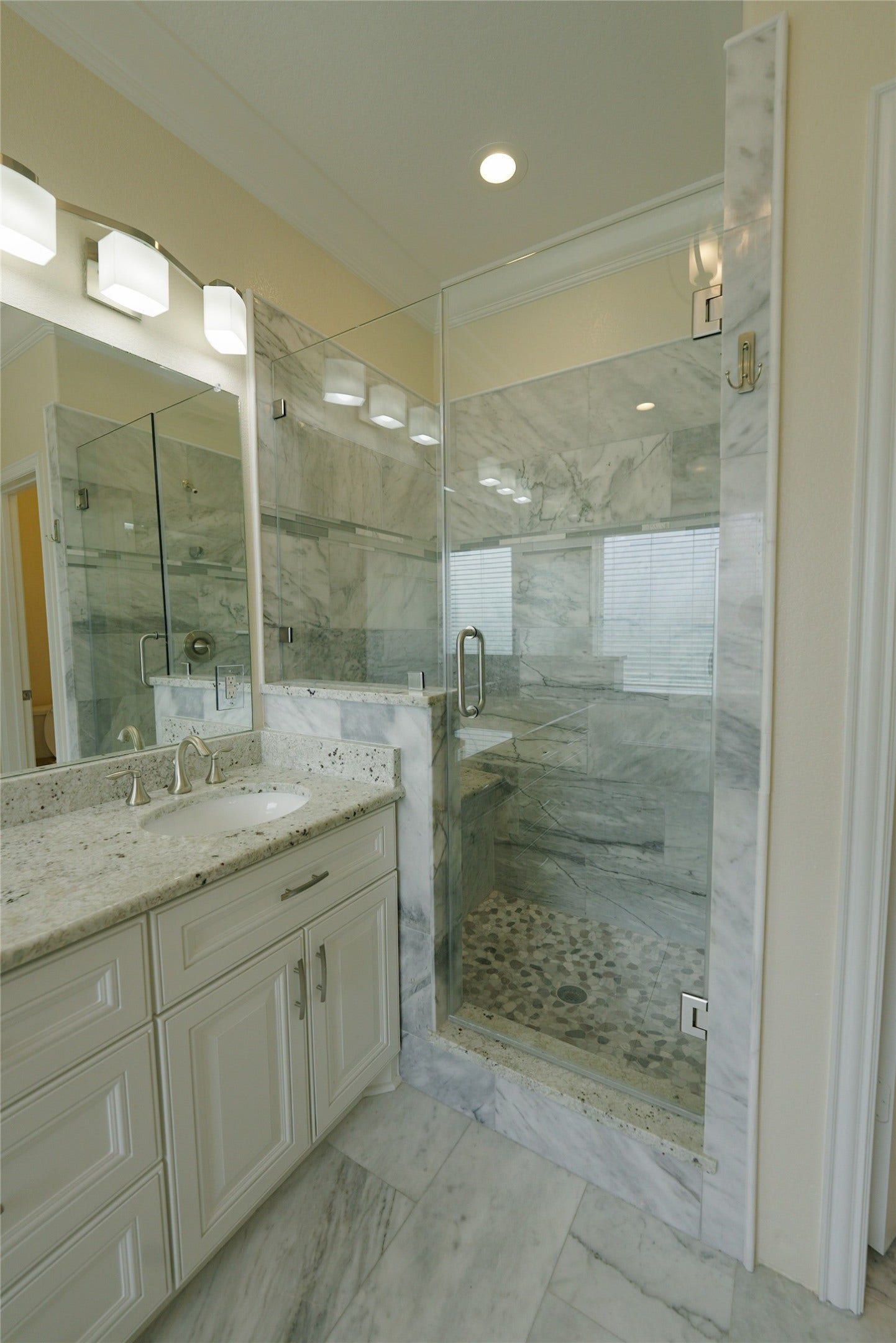 1013 10th Street, Galveston, TX 77550 Luxurious top-level primary bathroom featuring a double vanity, jetted tub, elegant marble finishes, and recessed lighting. Currently tenant occupied.