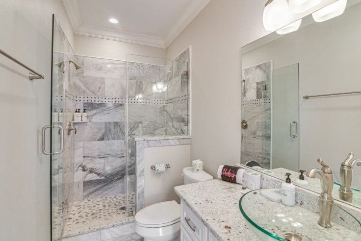 1013 10th Street, Galveston, TX 77550 Elegant guest bathroom featuring a luxurious marble shower, modern fixtures, and a chic glass sink for a spa-like retreat.